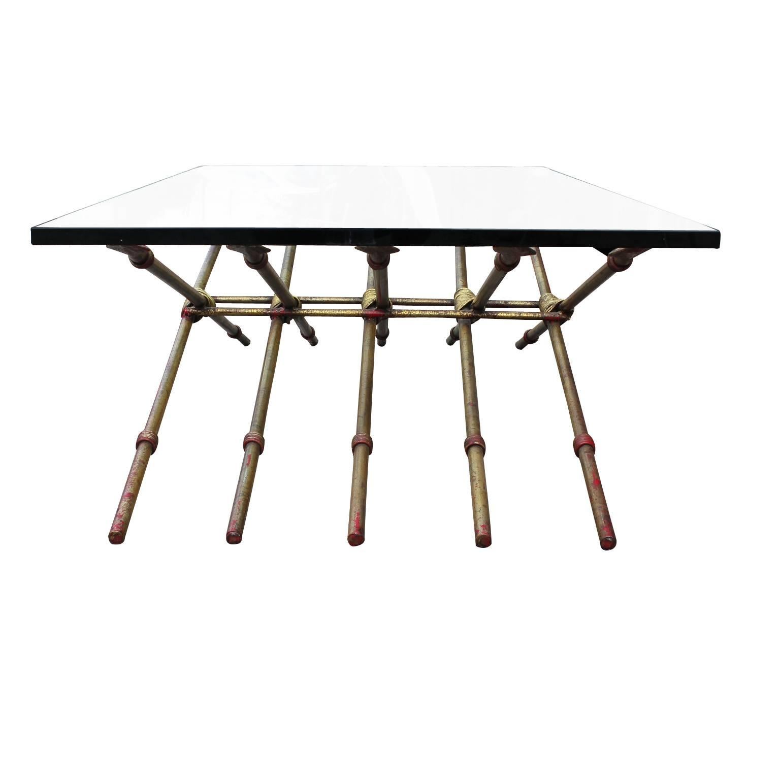 Ten gold leafed spears intertwined to make to a wonderful glass coffee table. The table is metal finished with a red underlay and gold leaf finish on top. The table has a Hollywood Regency or French feel to it. The gold spear table is in great
