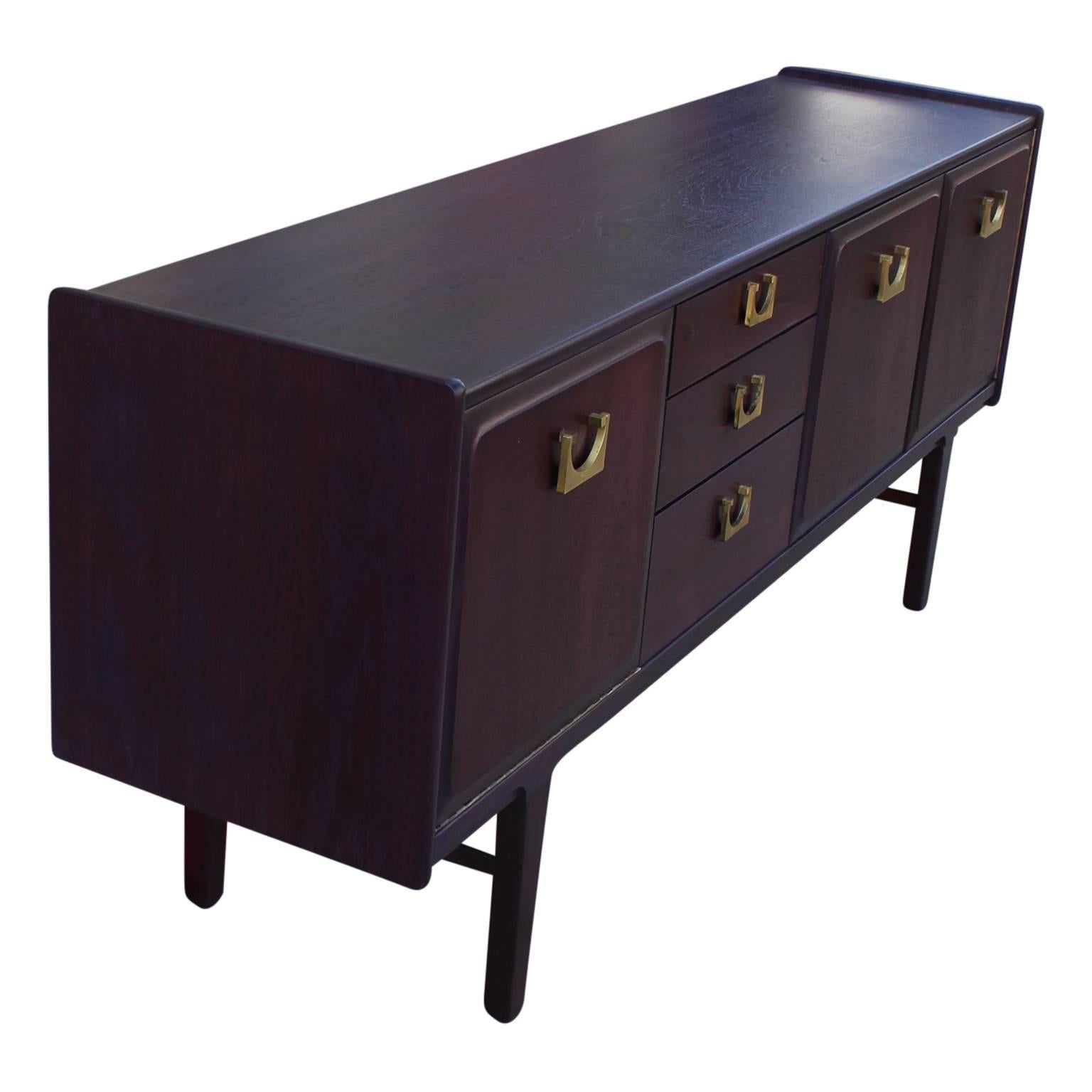 Excellent teak sideboard / credenza with brass hardware aniline dyed in a deep violet purple. The credenza features 3 doors with ample storage and three drawers to left left center. The hardware is bold and tops off the great look. The construction