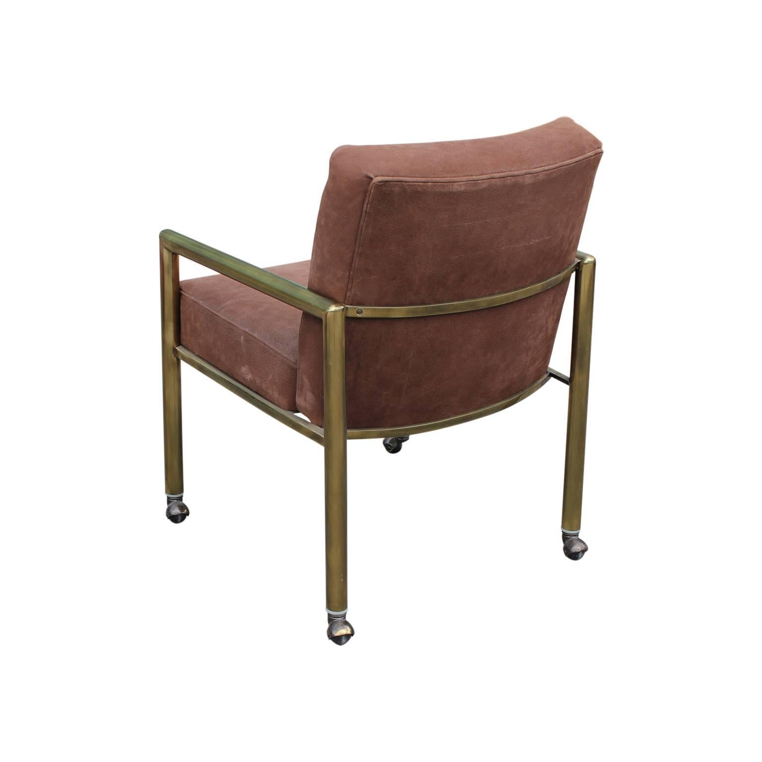 Pair of unique dining or lounge chairs featuring brushed brass and brown suede. These chairs are outfitted with wheels, but they can easily be removed. Attributed to Mastercraft.