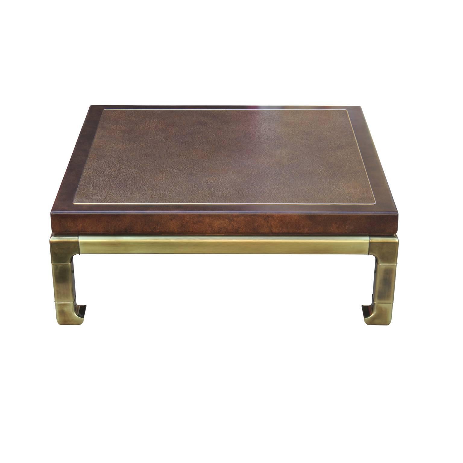 Gorgeous Mastercraft brass coffee table with a brown lacquer faux skin leather top with brass band inlay. Base features brass frieze and legs.