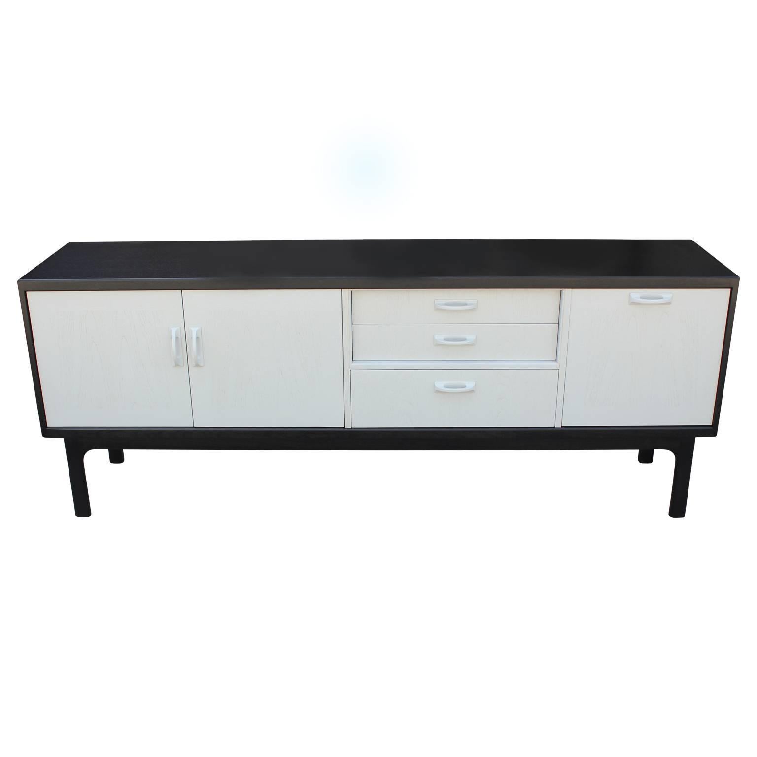 Gorgeous sideboard or credenza that has been restored in lovely black and grey stain. This piece features two cabinet doors that open to reveal a single self, three drawers and a drop door. The top drawer opens to reveal five organizational