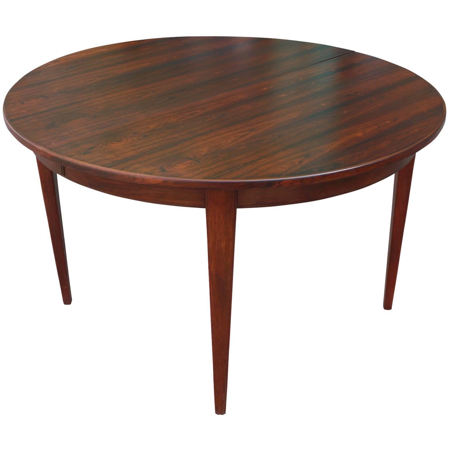 Rosewood dining table by Omann Jun. Table is round without leaves. One rosewood leaf and two ebonized leaves. Ebonized leaves create an interesting two tone effect. Table with no leaves measures 47.5 in. wide and with all three leaves measures 106