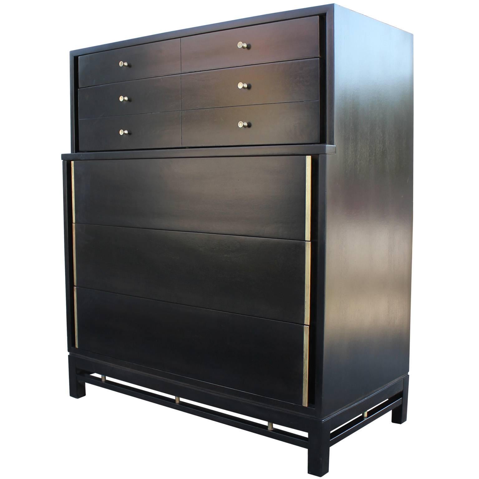 Stunning chest by American of Martinsville. Dresser is finished in a dark ebony stain in satin. Delicately polished brass adds wonderful contrast. Negative space along base adds visual interest. Five large drawers provide ample storage. Top three