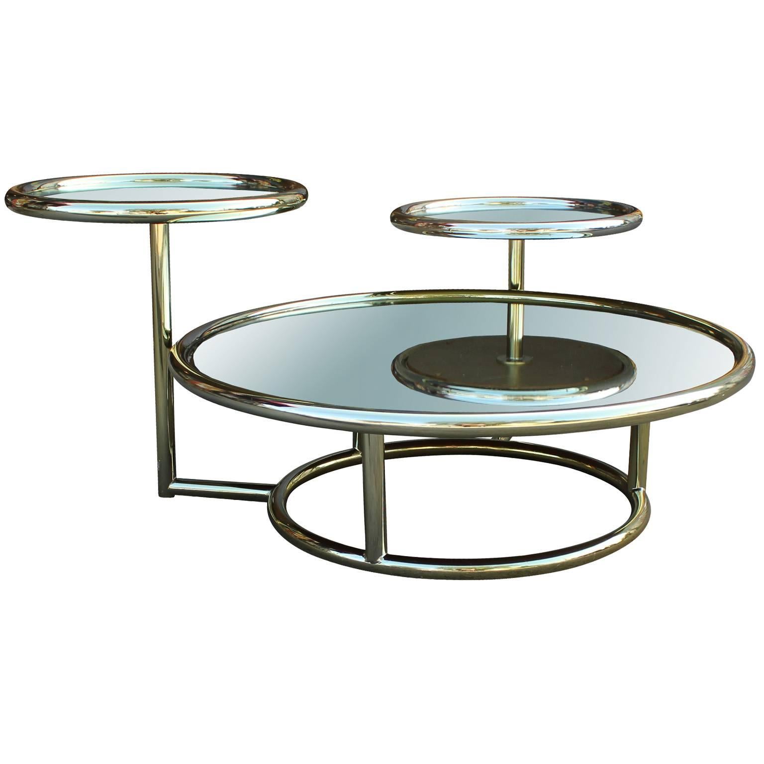 Striking multilevel brass and mirror coffee table. Shiny brass tubes are in great vintage condition. Coffee table measure 10.25 in. tall, while the smaller circles meausre 15.75 in. and 18.75 in. tall. Striking piece with playful lines.