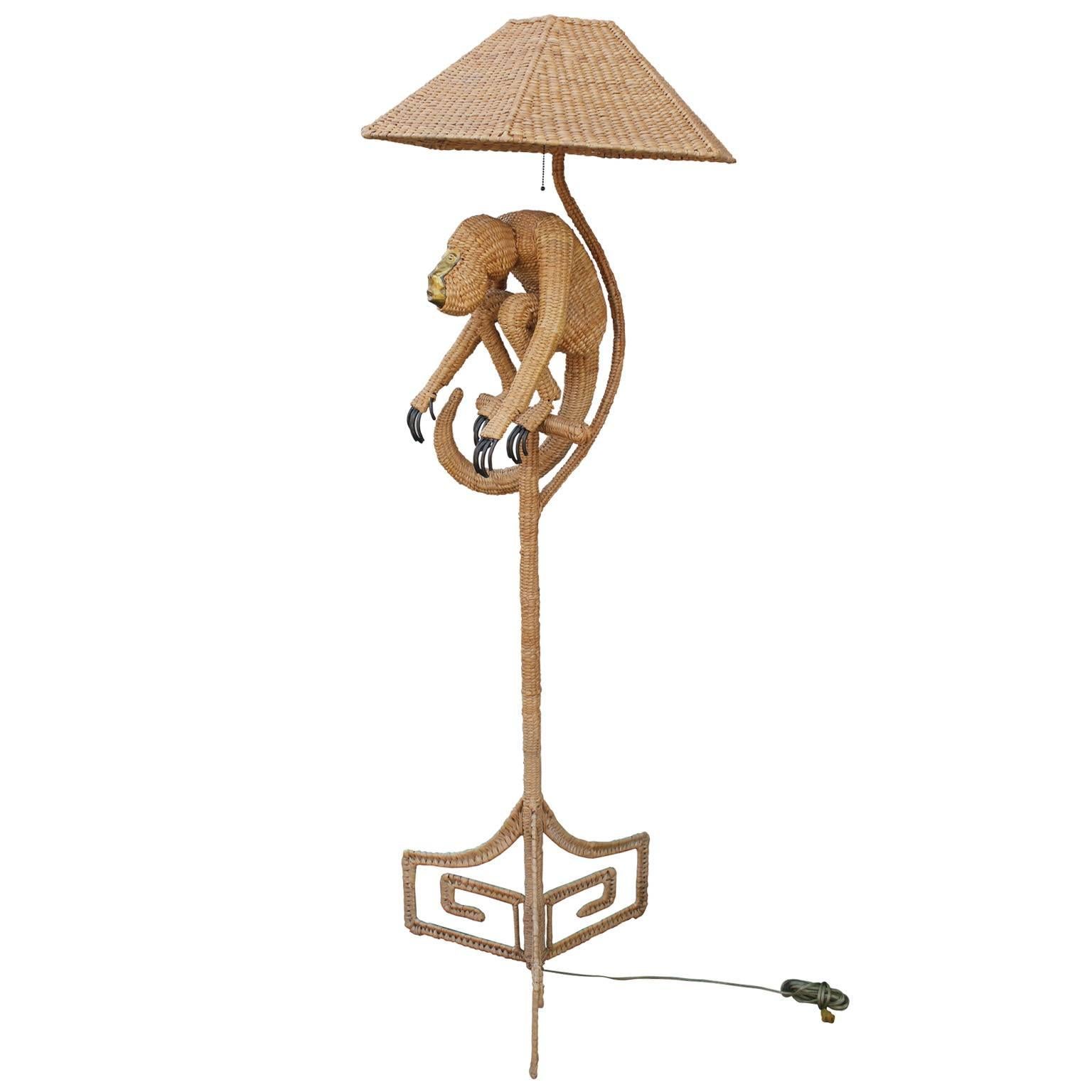 Vintage Mario Lopez sculptural wicker floor lamp featuring a monkey and Greek Key base. Monkey has an expressive brass face and iron fingers and toes. Great statement piece.