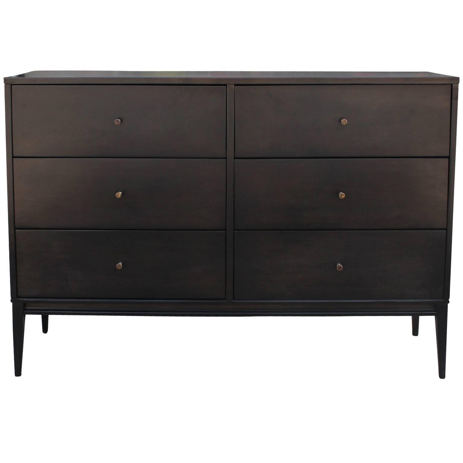 Wonderful dresser by Paul McCobb for Planner Group. Dresser is finished in an black ebony stain. Brass pulls add contrast to the piece. Delicate tapered legs finish the piece. Six deep drawers provide ample storage. Retains original labels.