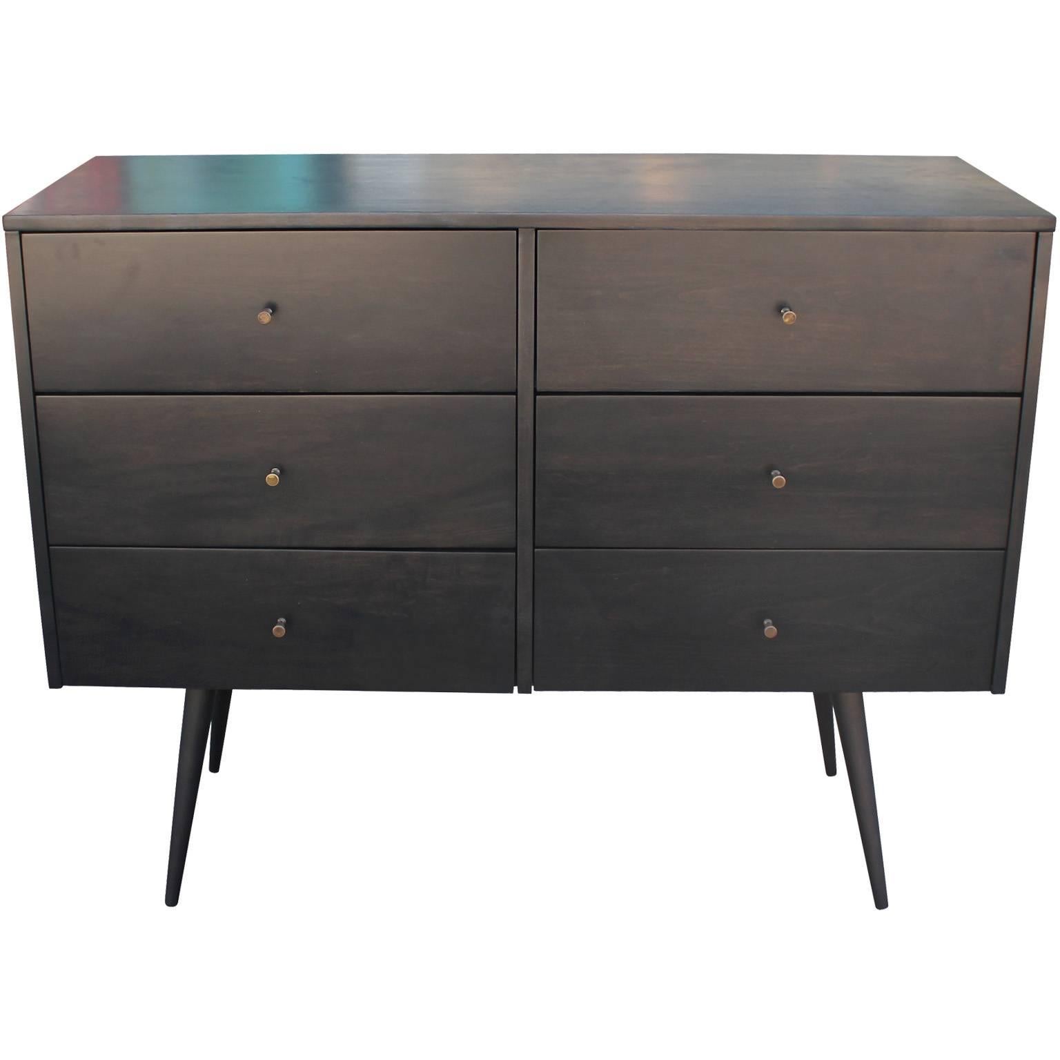 Wonderful dresser by Paul McCobb for Planner Group. Dresser is finished in an ebony black stain. Brass patinated pulls add contrast to the piece. Delicate tapered and splayed legs finish the piece. Six deep drawers provide ample storage. Retains