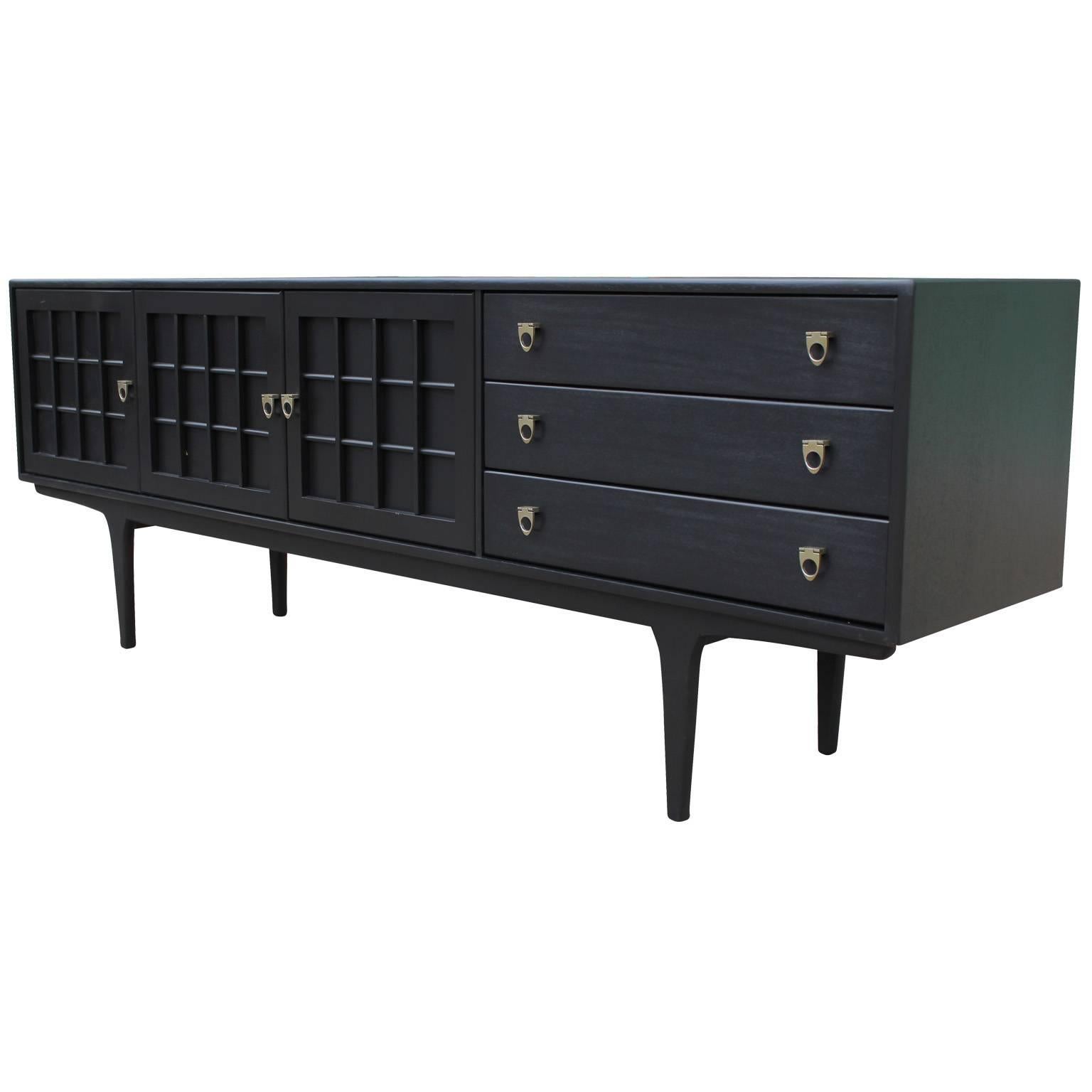 Ebony stained with brass handles. Sideboard / Credenza is finished in black lacquer with the grain still showing. Fully restored. Three cabinets doors and three drawers provide excellent storage. Aged brass hardware. 