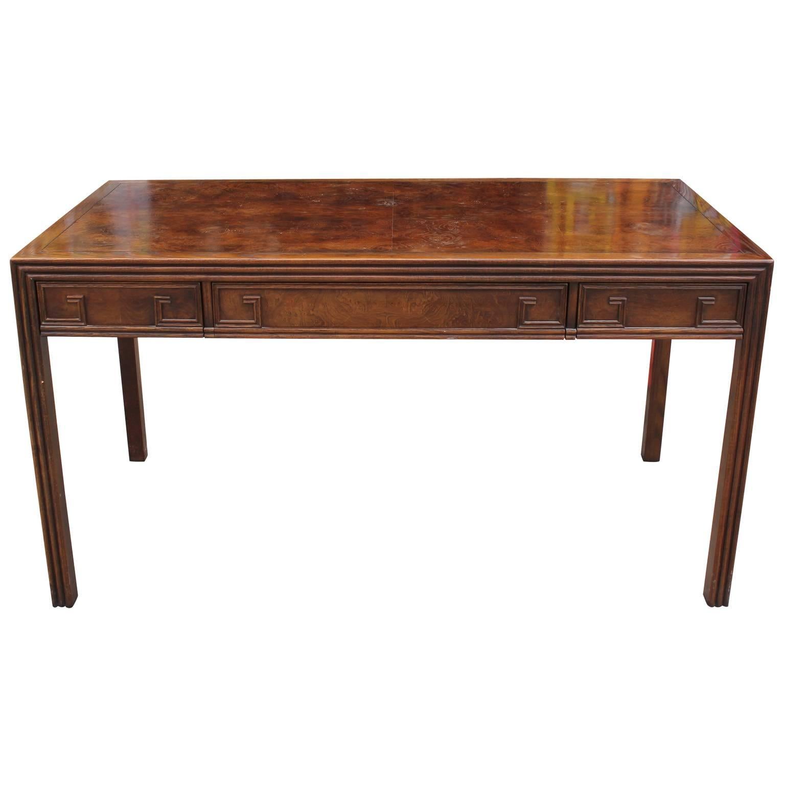 Wonderful clean lined desk. Desk has a dramatic burl wood top. A carved Greek key motif adorns all four sides of desk. Three drawers provide storage. Excellent attention to detail makes this the perfect transitional piece. Made by Baker Furniture
