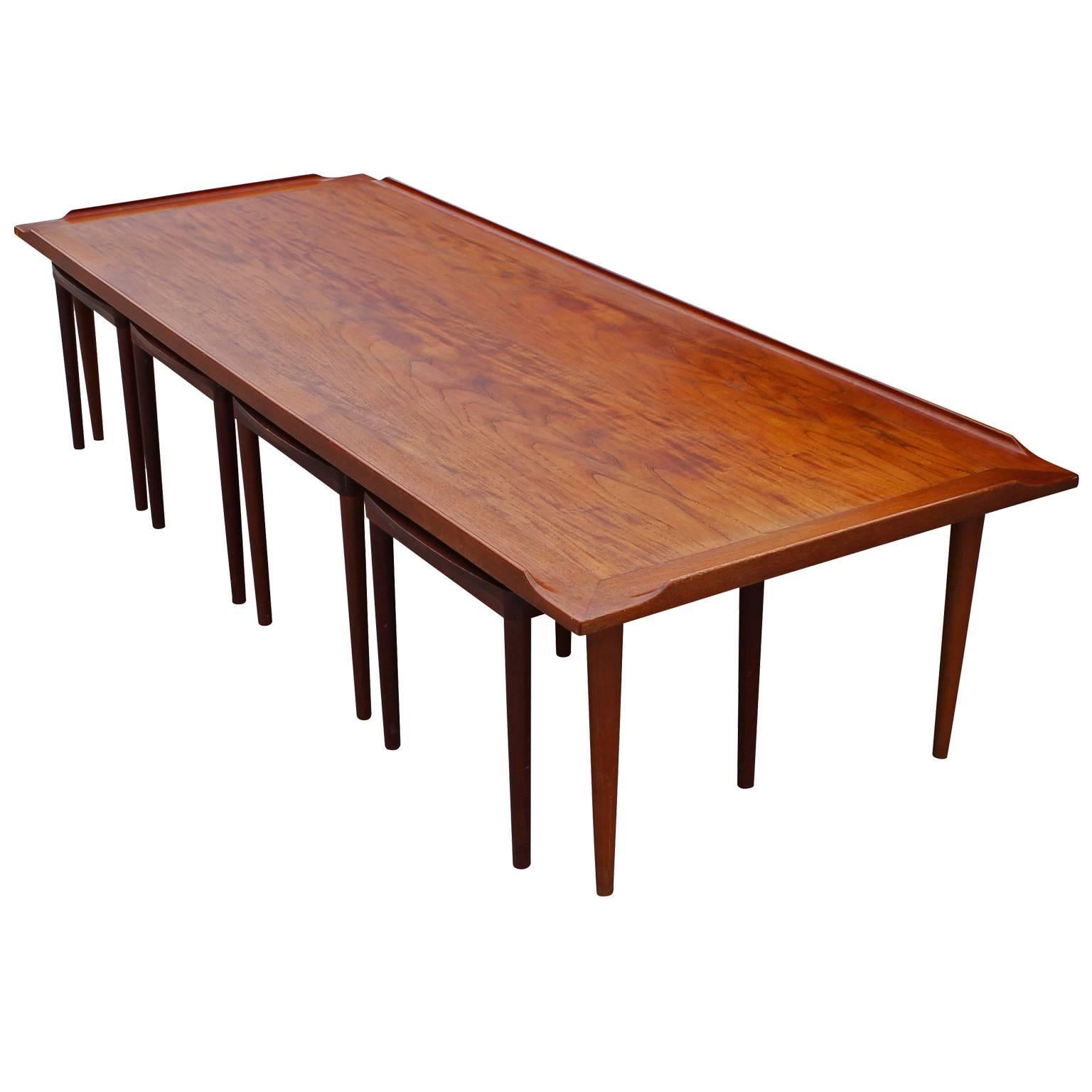 Rare large teak coffee table made in Denmark with four removable stools/ side tables. The table has elegant curved lip on the top with beautiful grain. Four removable tables store underneath. Each table has top that can flipped to show a vintage