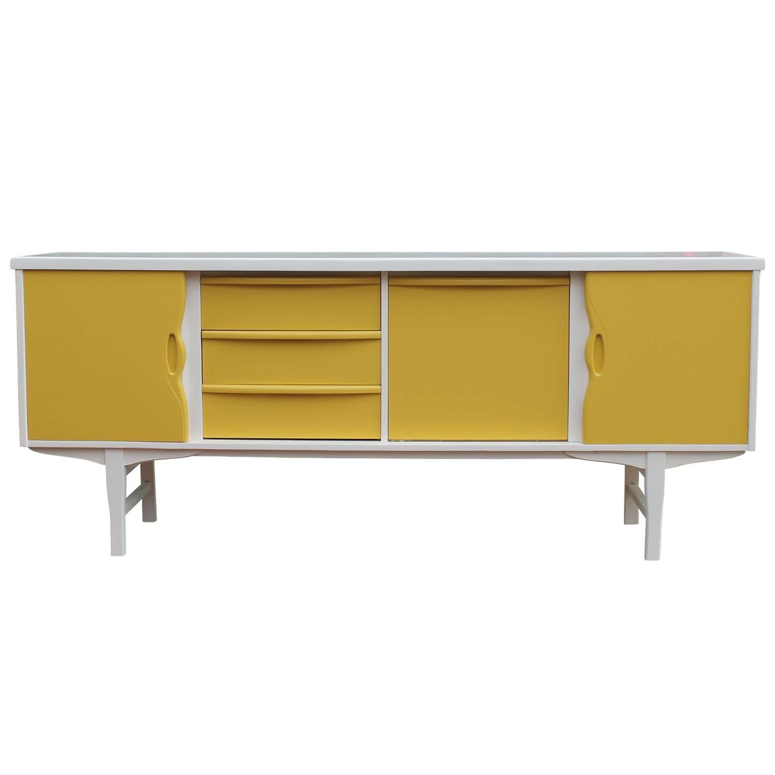Stunning credenza freshly lacquered in cream and mustard colors. Two sliding doors open to reveal a single shelf. A drop down door hides bar space complete with mirror and glass shelf. Three Drawers provide additional storage; top is slotted for