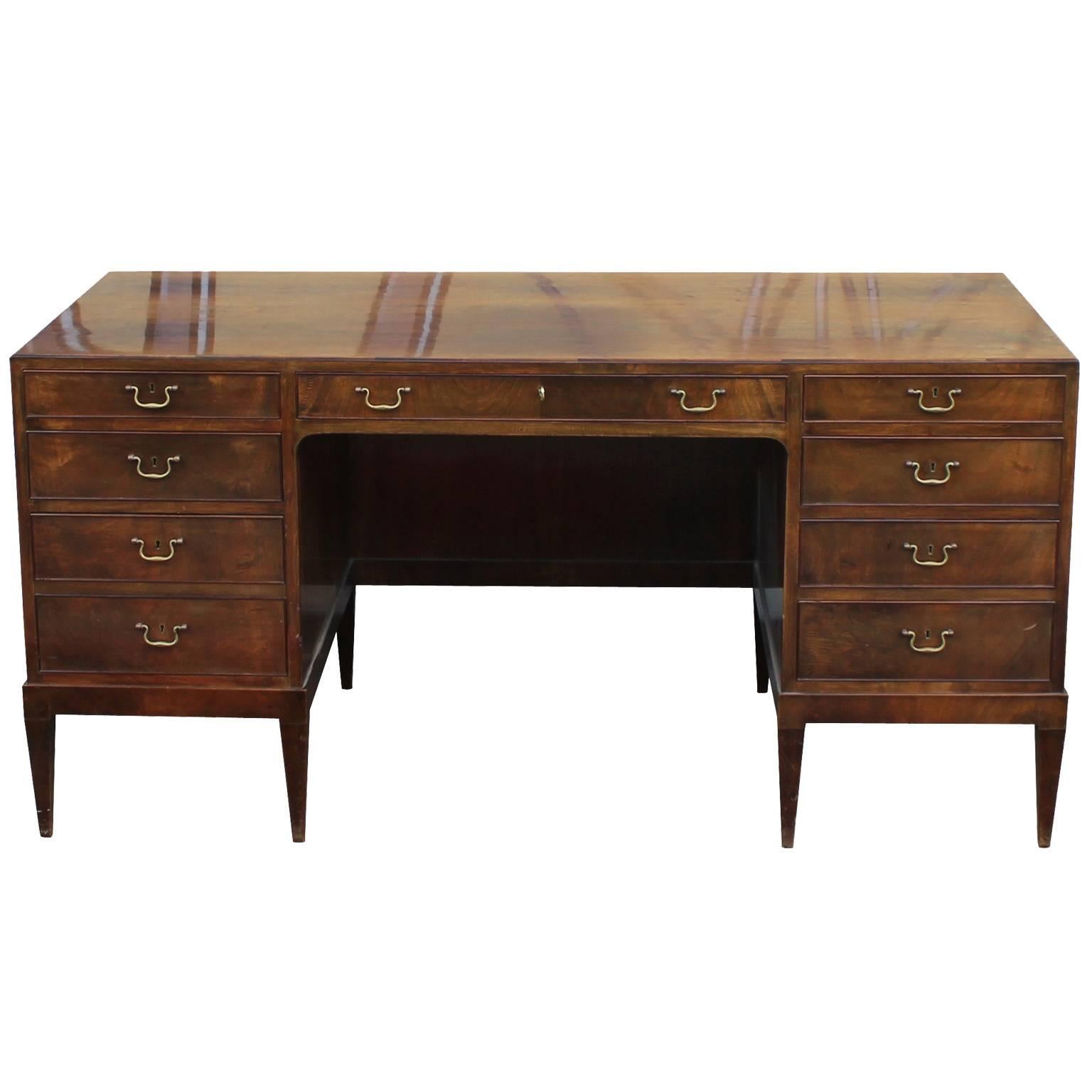 Stunning Frits Henningsen executive desk in mahogany with brass hardware. Desk is topped with a long single drawer and flanked with four graduated drawers on either side. Raised on square tapered legs. Original finish, The top has some sun faded