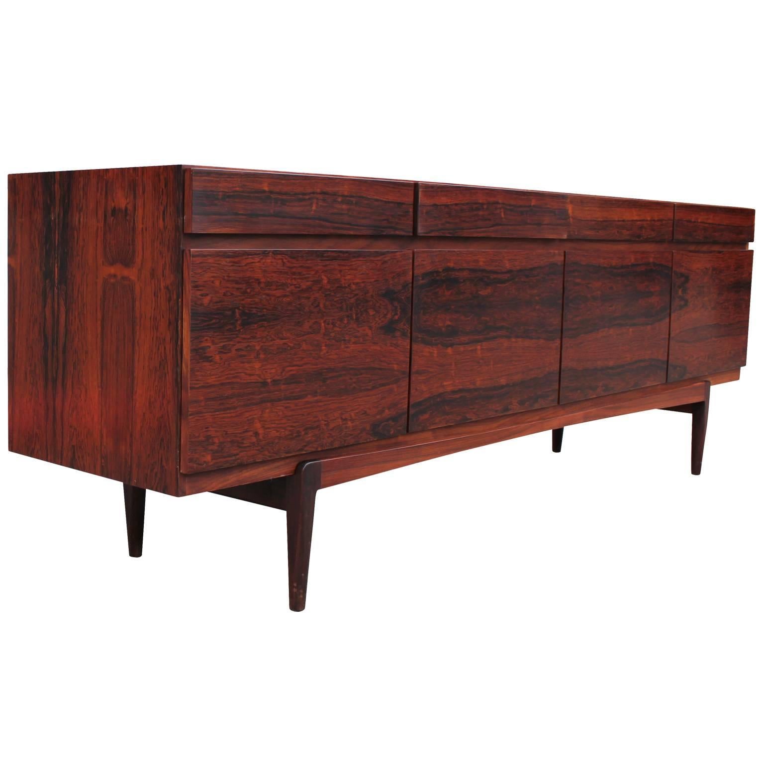 Rosewood sideboard Model FA66 by Kofod Larsen for Faarup Mobelfabrik. Stunning grain is book matched across the front doors and drawers. Features four upper drawers and four lower cabinets. Far left cabinet opens to reveal felt lined drawers.