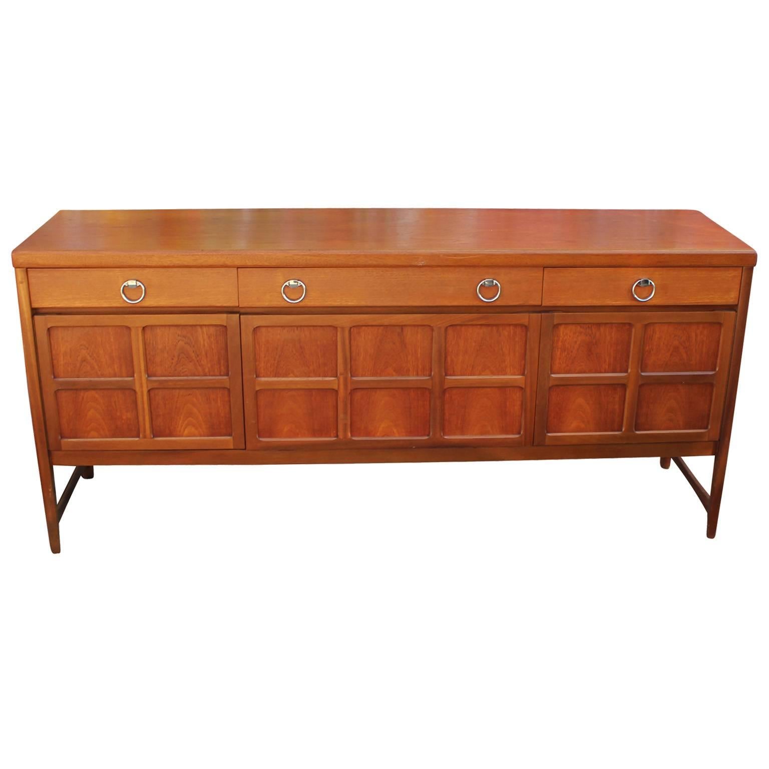 Wonderful sideboard or credenza with shiny chrome ring pulls. Sideboard is constructed of mahogany and teak. Front middle cabinet door drops down to reveal a single shelf. Right and left cabinet doors open to a single shelf. Three drawers provide
