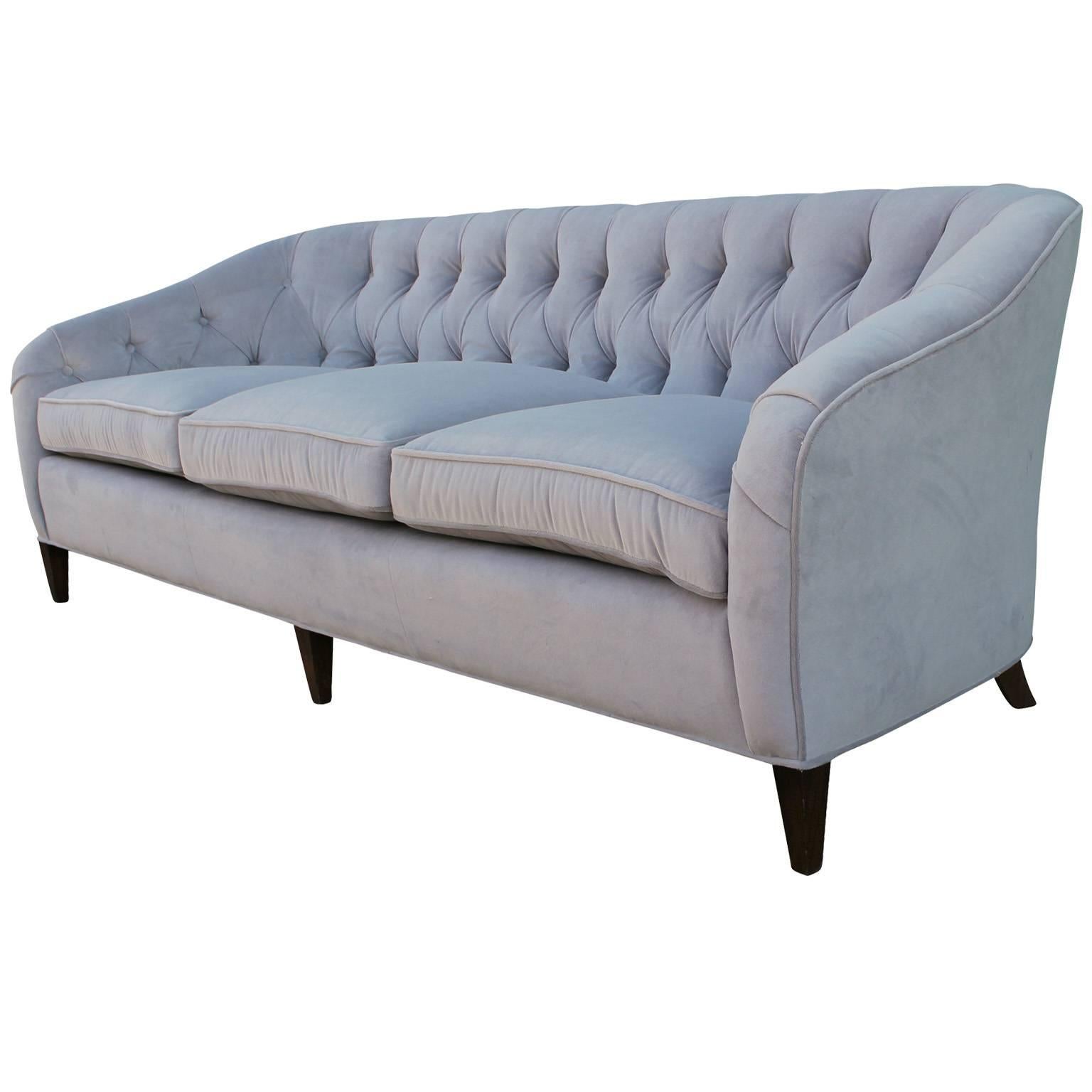 Glamorous and comfortable sofa by Baker Furniture. Sumptuous and comfortable cushions. Tufted sofa is freshly upholstered in a soft pale grey velvet mohair. Dark walnut legs finish the piece.