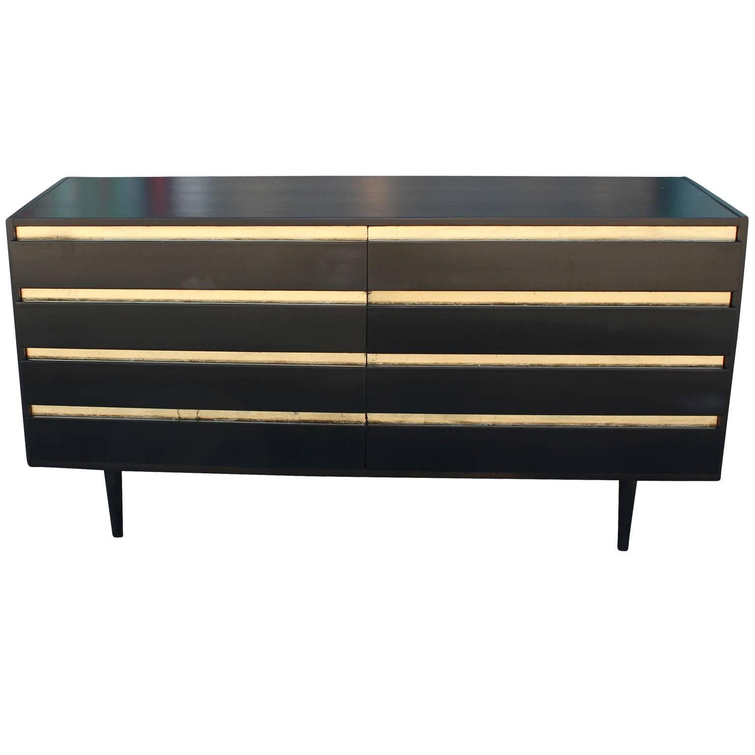 Wonderful dresser made by American of Martinsville in a custom ebony/black finish with hand gold leafed accents. The dresser has eight drawers and is very functional. The piece was made in the 1960s and has a lux Hollywood Regency feel. In excellent