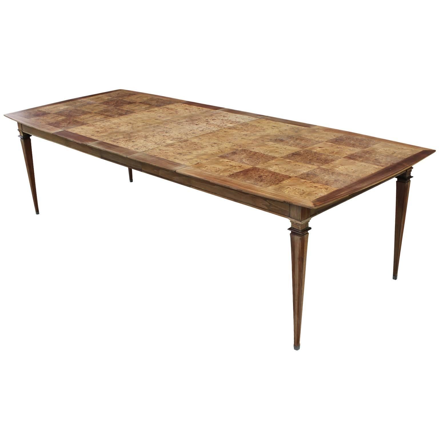Stunning dining table designed by Bernhard Rohne for Mastercraft. Elegant burled walnut and copper dining table. Tabletop has a slight boat shape and features checkered burl parquetry. Leaves have matchbook burl veneer. Dramatically tapered legs are