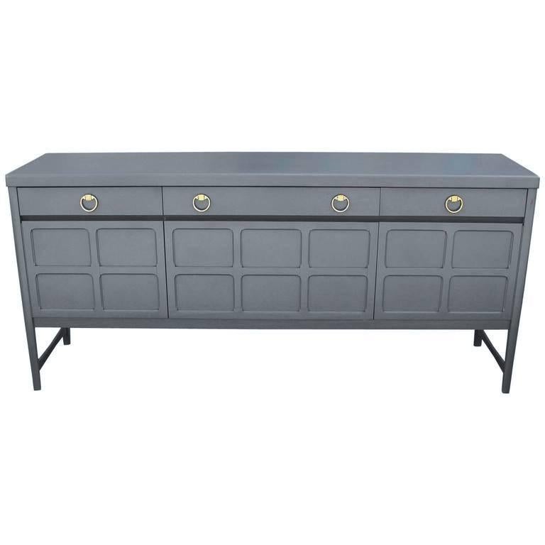 Excellent sideboard or credenza freshly finished in a French blue grey. Four patinated brass ring pulls. Sideboard or credenza is constructed of mahogany and teak. Middle cabinet door drops down to reveal a single shelf. Doors on either side open to