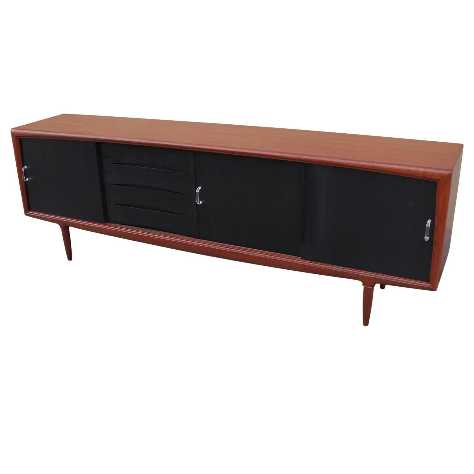 Two-tone credenza / sideboard with sliding doors and shelving perfect for organization and storage. Made in Denmark in the early 1960s. The sideboard has been slightly customized with a charcoal stained front and lucite handles. 