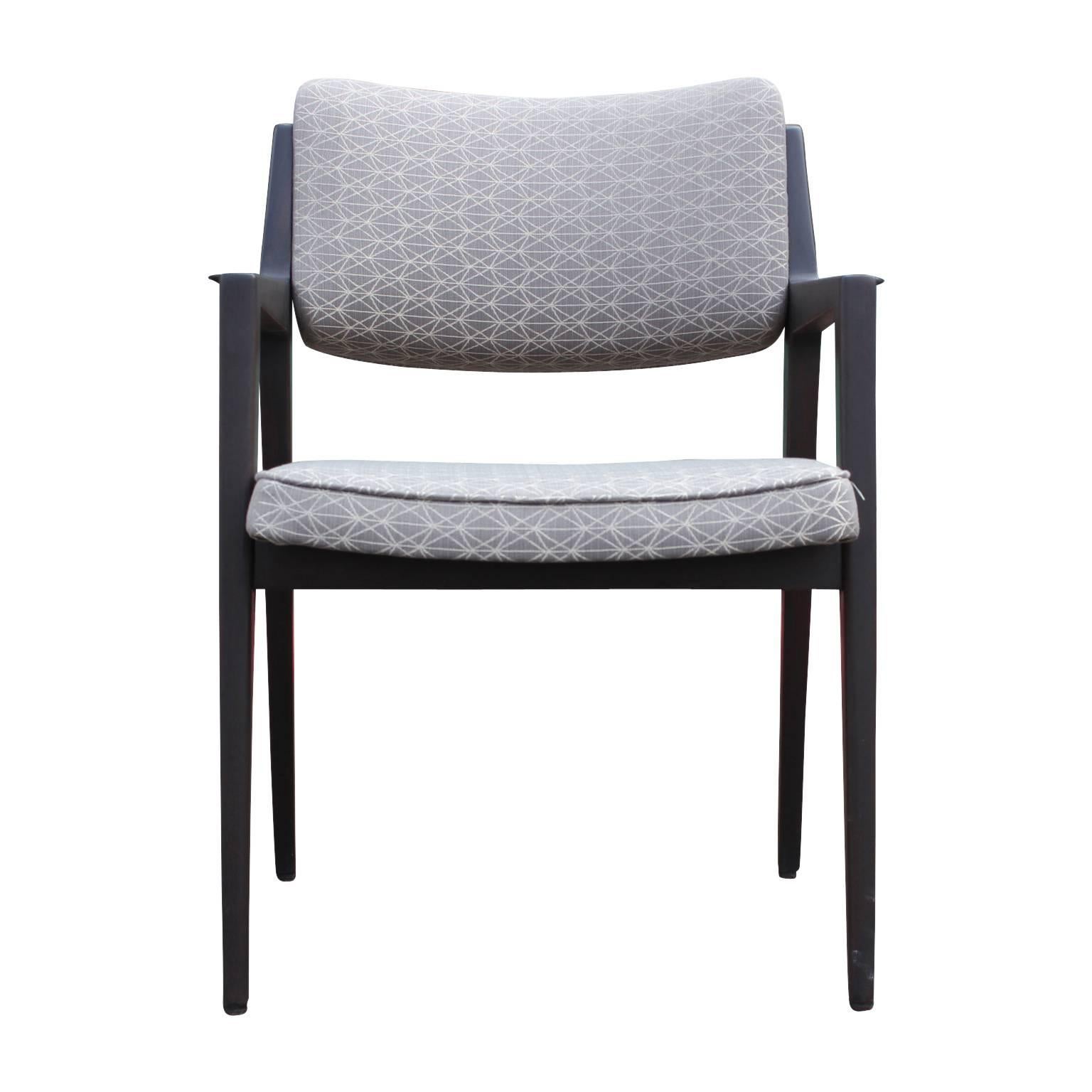 Set of four Italian modern dining chairs recently reupholstered in a chic modern fabric. The chairs all have arms and have been refinished in a charcoal stain.