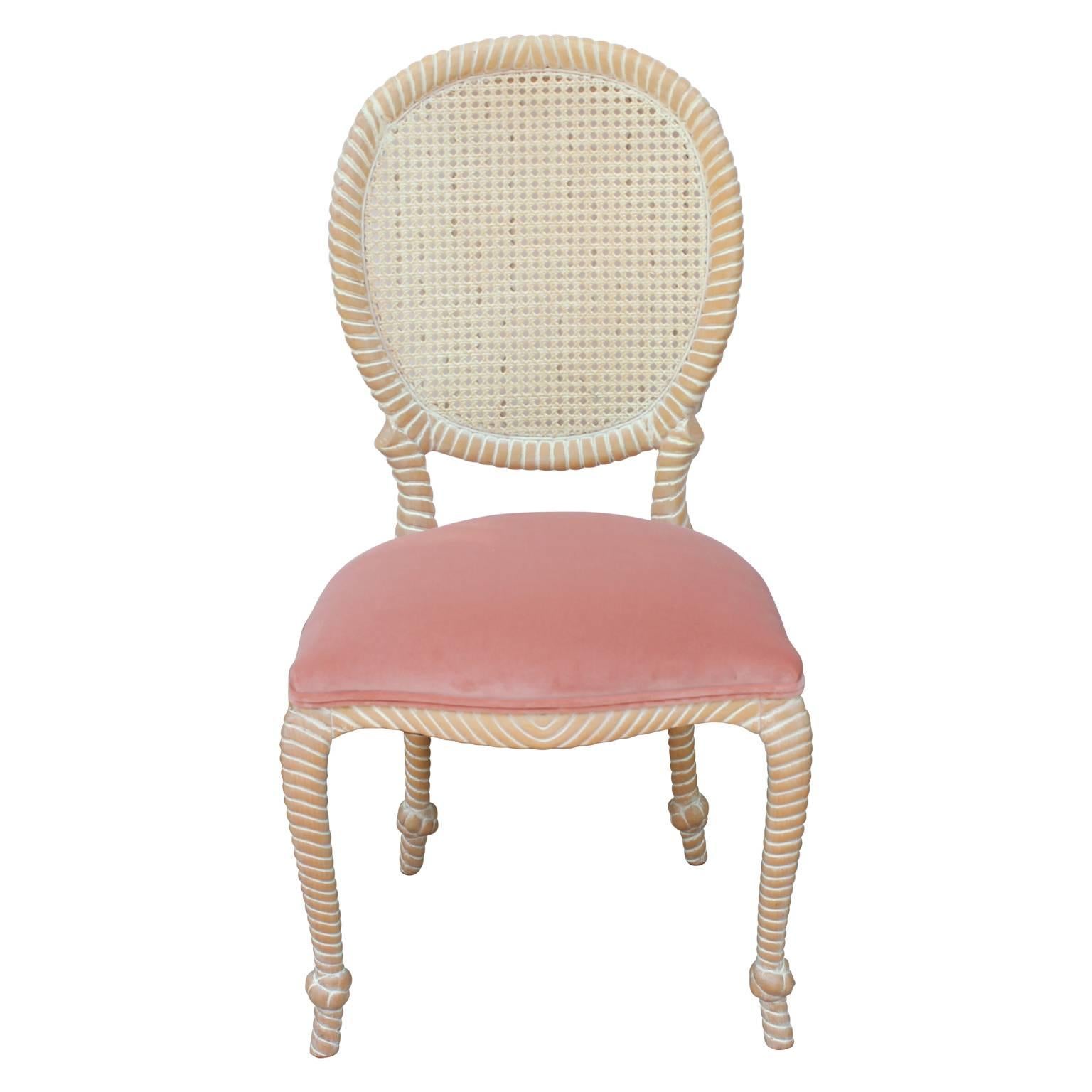 Set of five or four very unique dining chairs in bleached white washed wood that has been artfully carved with round cane backs and recently reupholstered in a beautiful light pink Kravet velvet. Such a lovely pairing of colors. Can sell just four