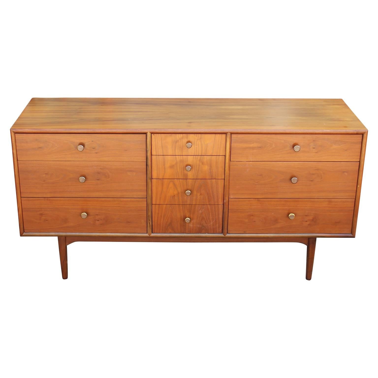 Beautiful walnut ten-drawer dresser by Kipp Stewart and Stewart McDougall for Drexel's Declaration line. Beautiful walnut wood grain with brass and faux wood pulls. Featuring four small drawers in the center and three larger drawers on either side,