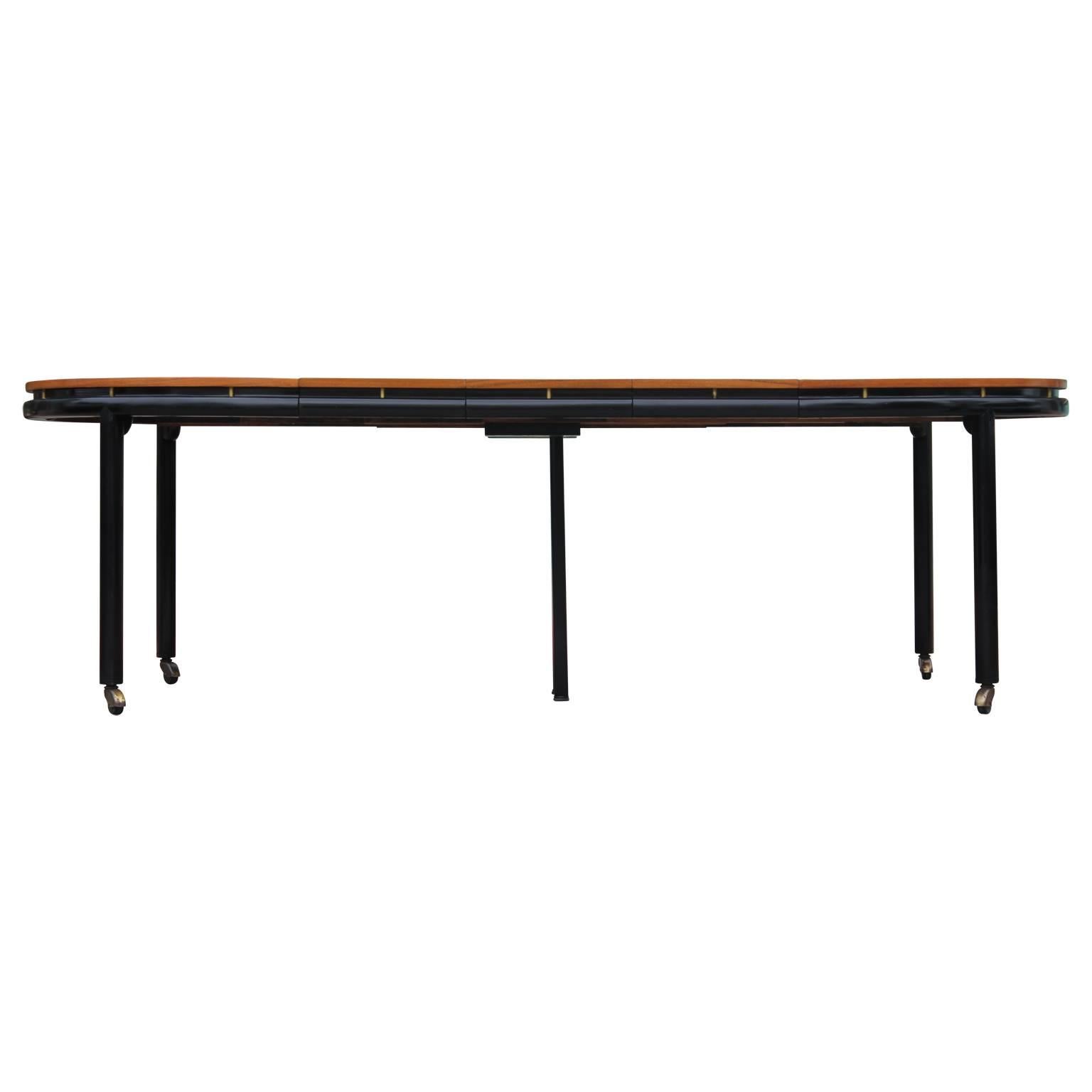 Gorgeous two-toned walnut dining table with three leaves by Michael Taylor for Baker Furniture New World Collection. With an ebonized finish on legs and brass castors. Measurements taken with all three leaves in place. Each leaf is 14 inches wide.