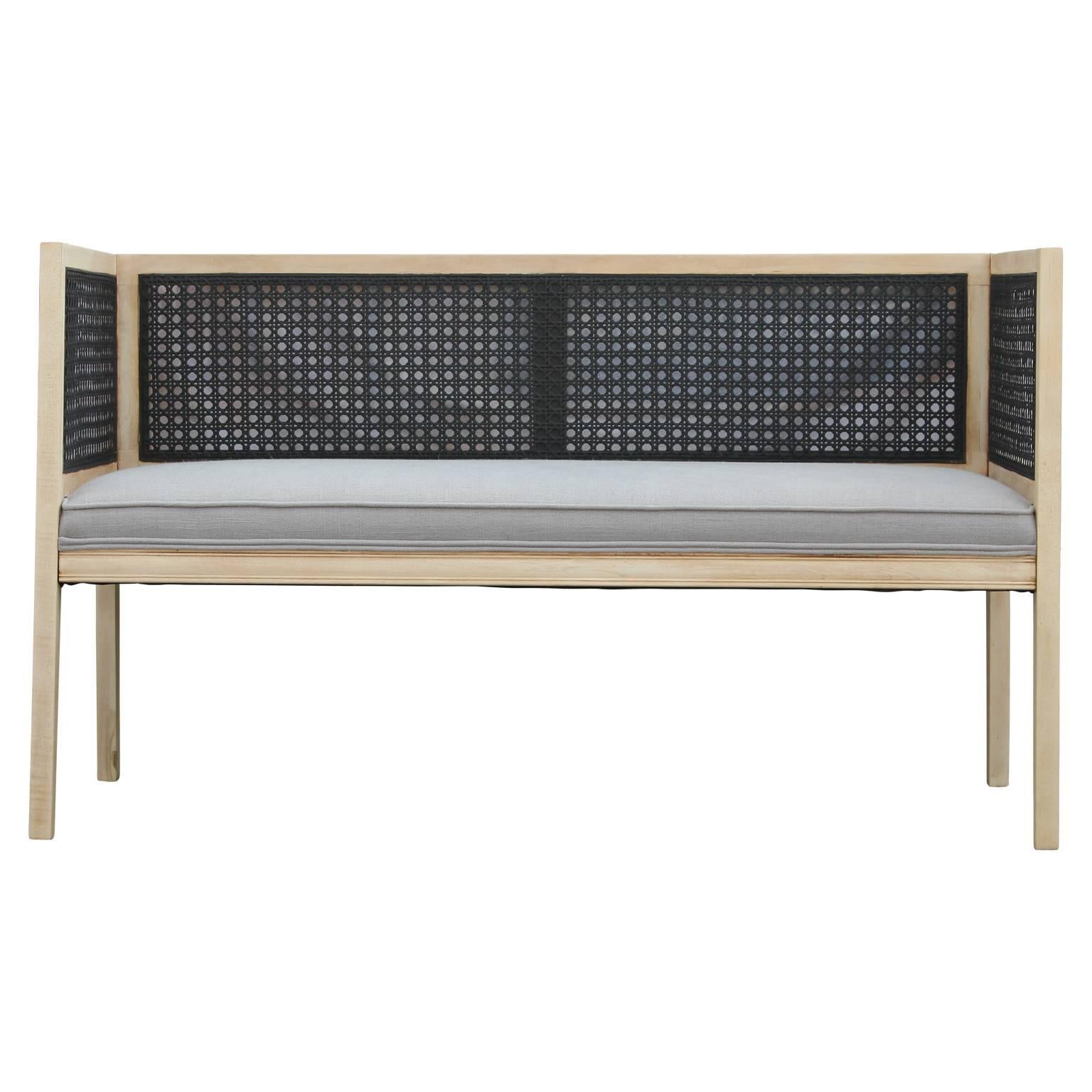 Modern cane and bleached wood settee or love seat in light grey Krypton fabric. In the style of Edward Wormley for Dunbar. The black cane offers a lovely contrast to the bleached wood frame and has been expertly upholstered. 