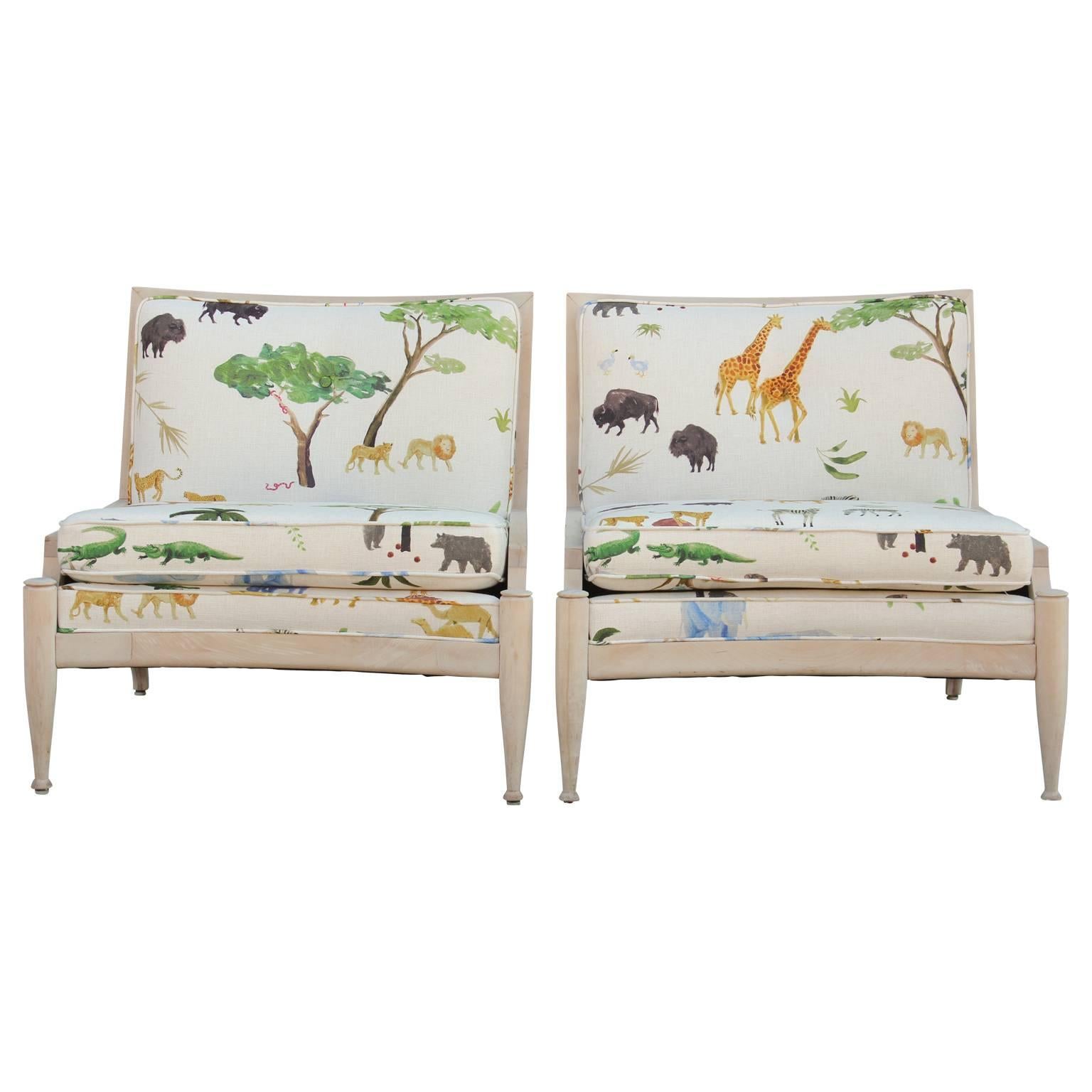 Pair of beautiful bleached wood lounge chairs with black cane sides. Freshly and expertly upholstered in a colorful print featuring jungle animal scenes. In the style of Baker Furniture or Gio Ponti.