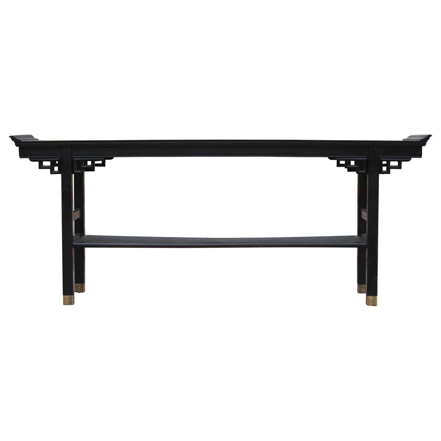 Modern two-tiered Pagoda style black console table with a cane shelf on the bottom and brass feet. Perfect console, sofa table or entryway table. 