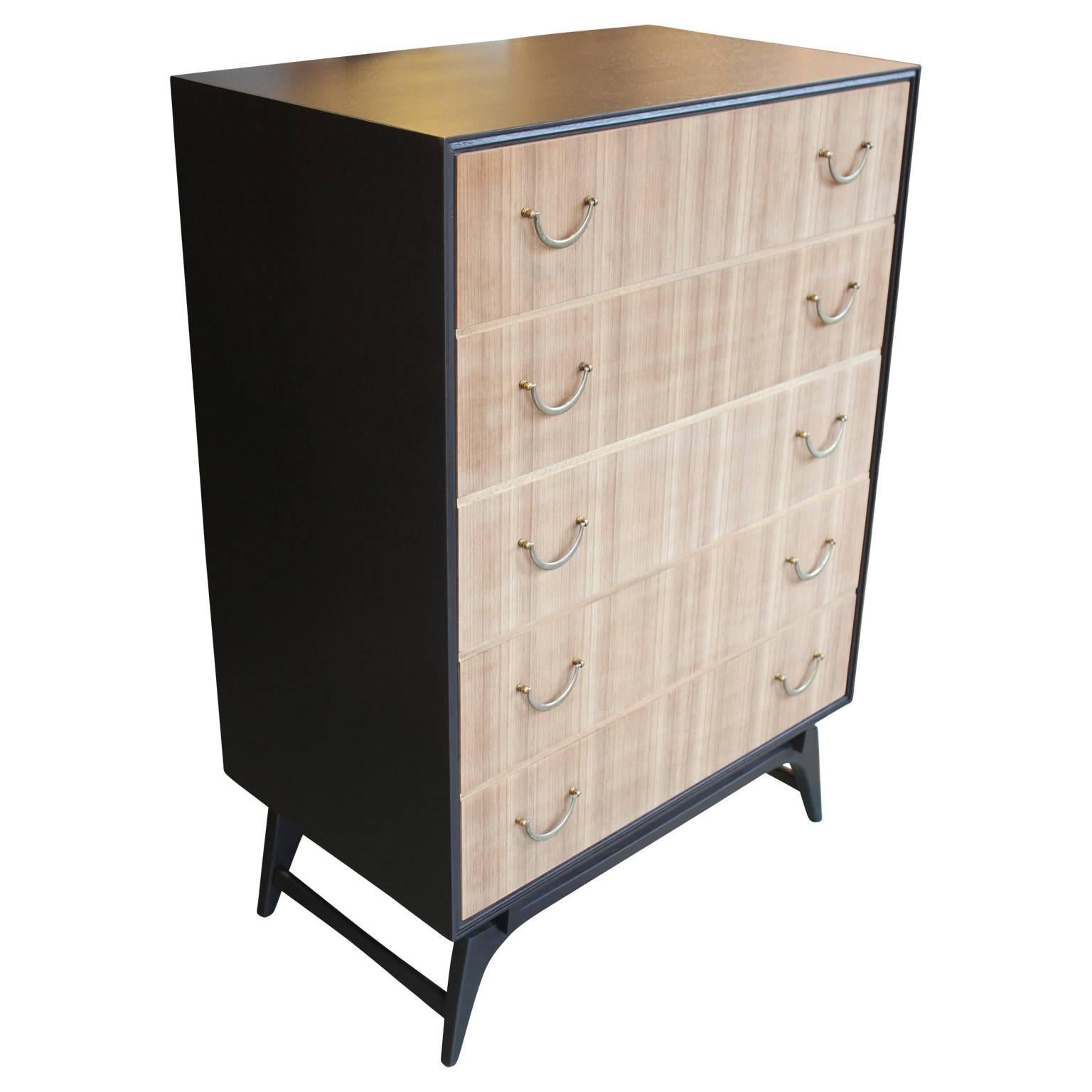 Gorgeous five-drawer bleached walnut dresser or chest of drawers in the style of Baker Furniture, Dunbar or Gio Ponti. This piece has been recently lacquered in a nice black and the drawer faces have been bleached. The hardware has a lovely natural