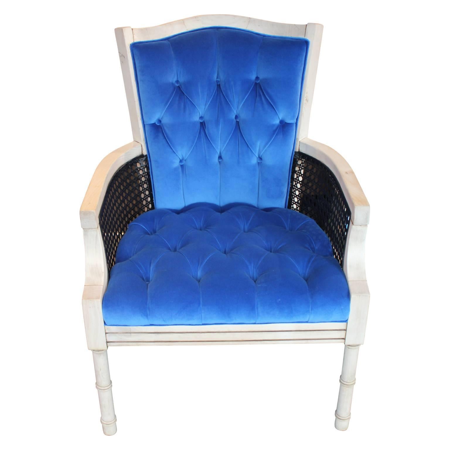 Lovely French cane lounge chair freshly upholstered and tufted in a lush blue velvet. The combination of the dark cane sides with the bleached wood frames offers a lovely contrast. The cane is in wonderful condition. 