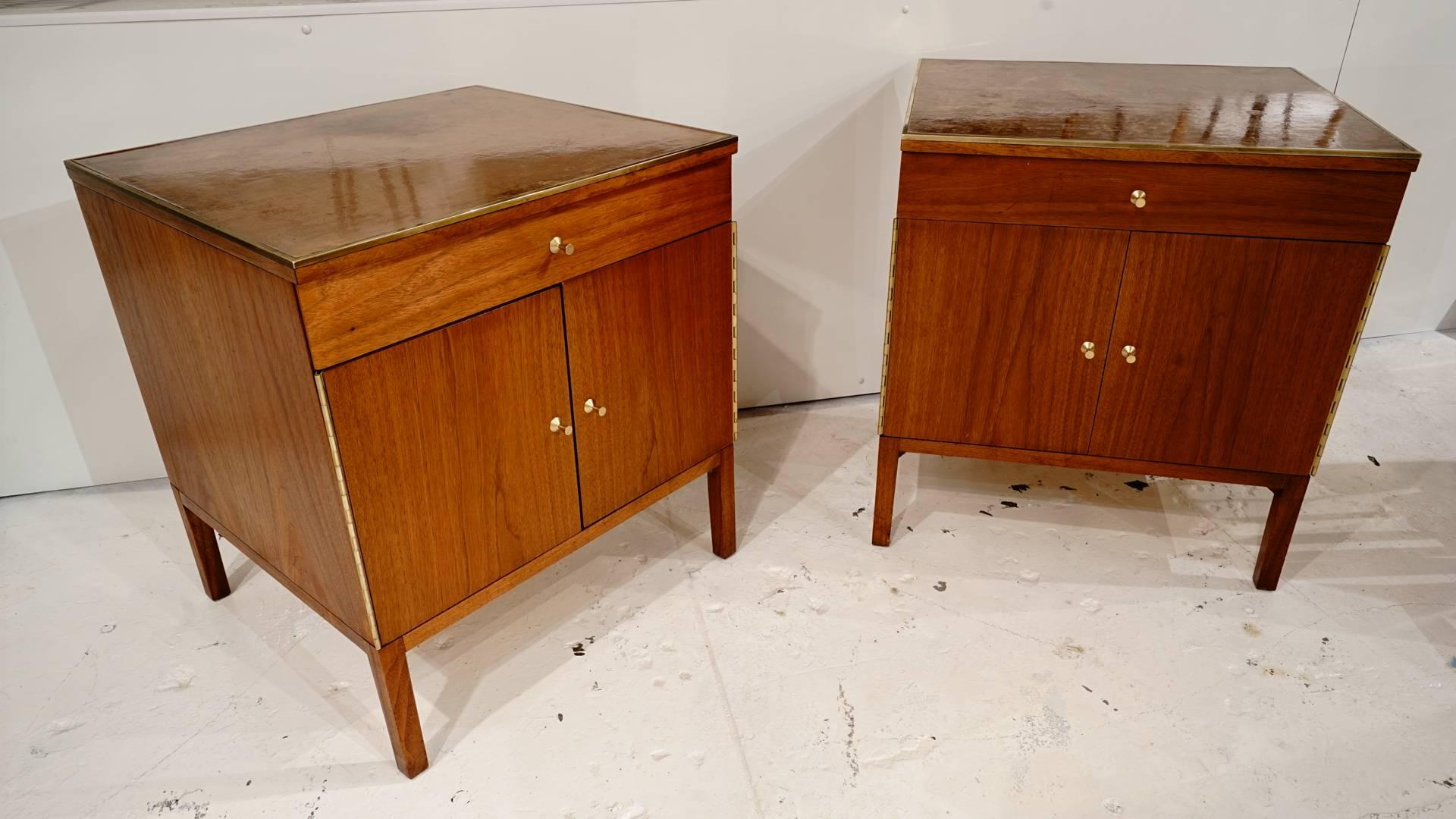 Matching pair of walnut Paul McCobb nightstands with a leather top and brass trim.