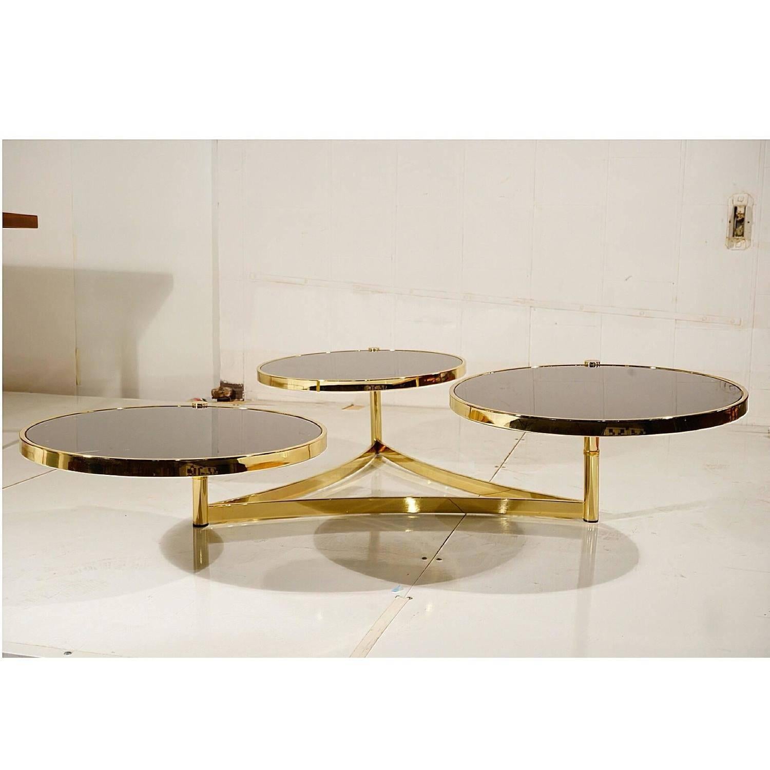 Absolutely gorgeous Milo Baughman for Design Institute of America. Newly refinished polished brass and black glass swivel coffee table. The black glass tops are inset within a brass frame. 

Each round saucer rotates in or out and when opened up