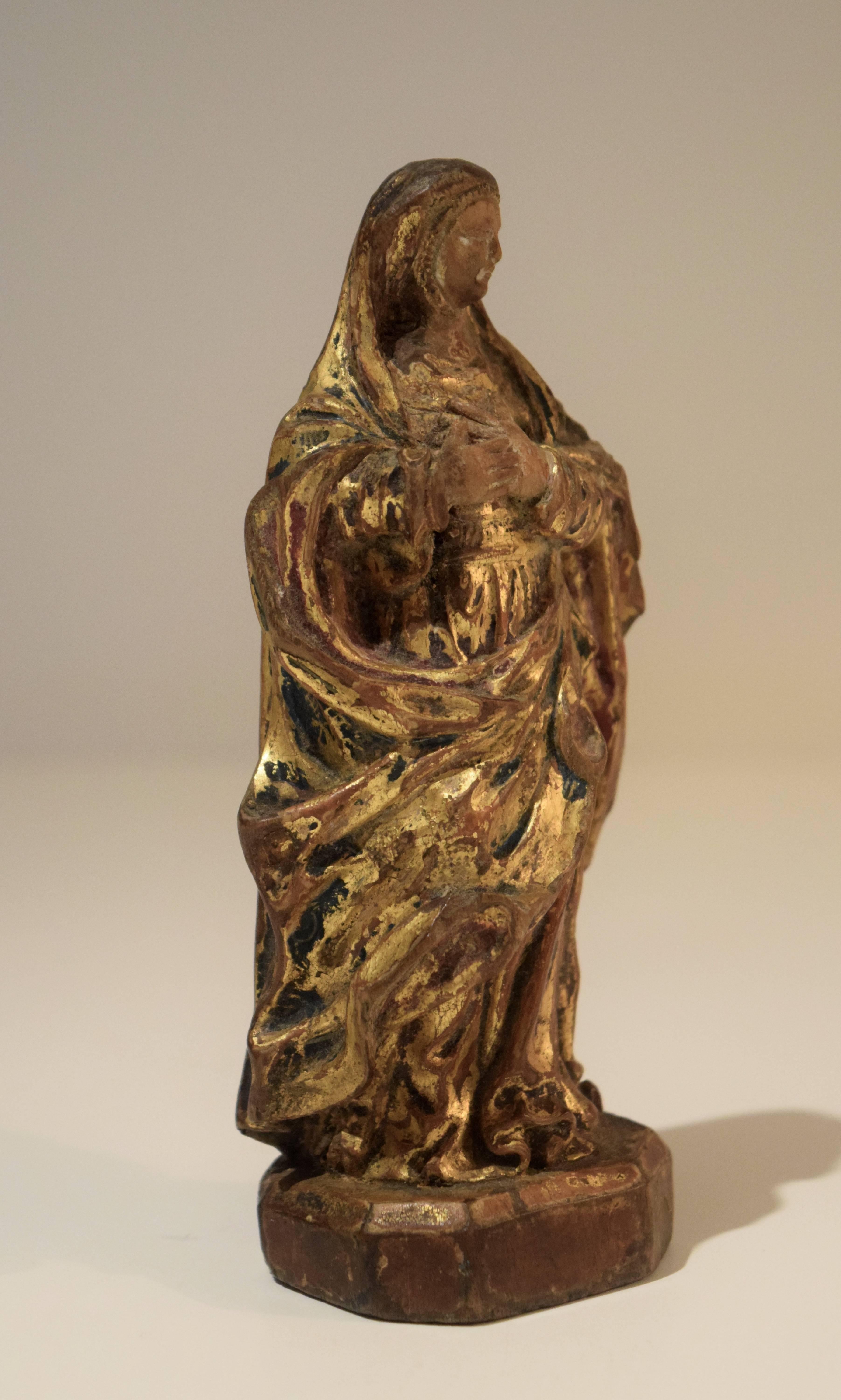 This charming, small, and very fine early 18th-century Flemish sculpture was carved from a single block of walnut. With the exception of the face it was fully gilded prior to painting the lining of the sleeves red, the dress blue, and partially