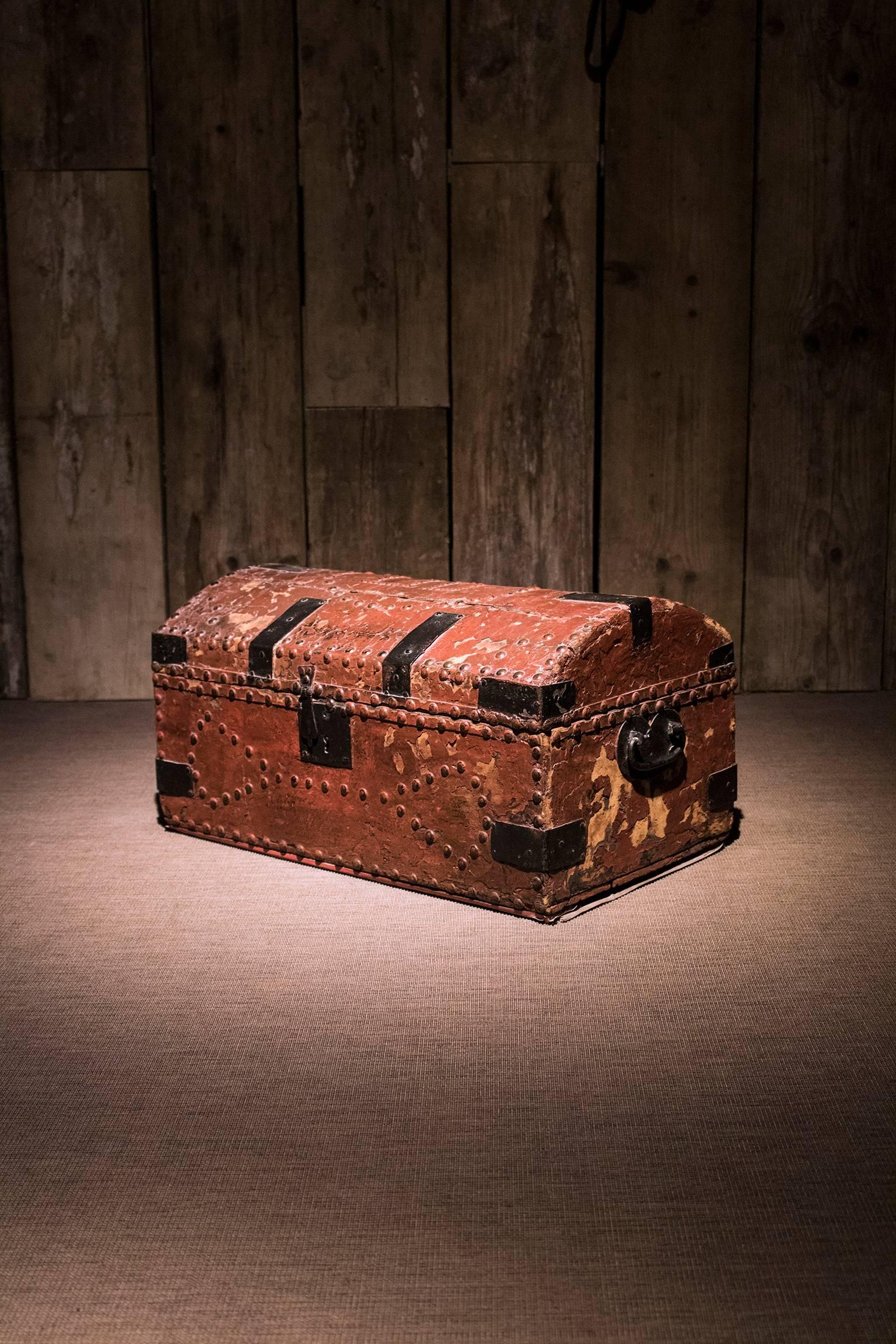 A Georgian studded red leather bound domed top small rectangular travelling trunk, the dome cover studded with a design spelling ‘LID’ in an oval studded mount and with further decorative studwork to the sides and cover and with various black metal