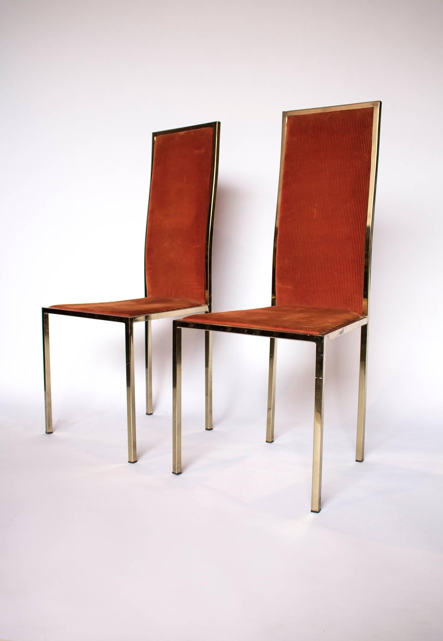 A pair of midcentury brass dining chairs in the Hollywood Regency style, upholstered in burnt orange velvet corduroy fabric, straight narrow brass edged back support with fine square shaped supports.