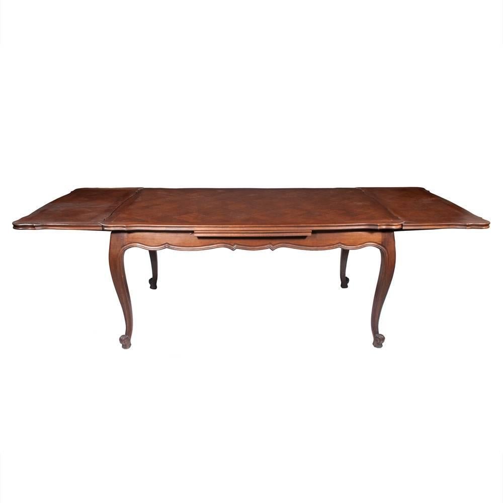 Country French oak draw-leaf table with parquetry inlaid top, scalloped apron and features cabriole legs. The table also has scroll, carved feet. Two leaves pull-out that are 18.5