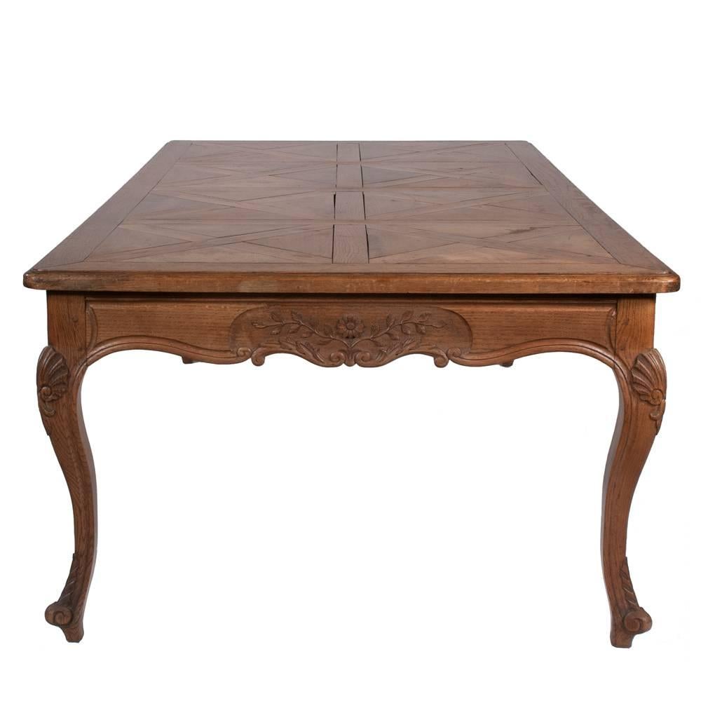 Country French solid cherrywood and elm farm house dining table with parquetry inlaid top, carved apron with Classic floral and leaf decoration, cabriole legs and scroll feet, circa 1900. Measures: 89