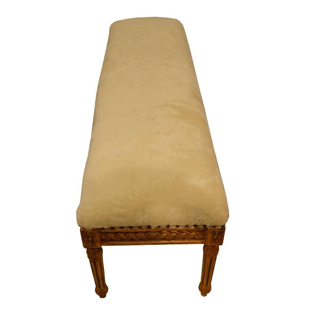 Louis XVI gold gilded bench featuring Classic fluted legs and a floral motif. The bench is upholstered in a cream mohair, with added nailhead studs. 
Seat height is 22.5