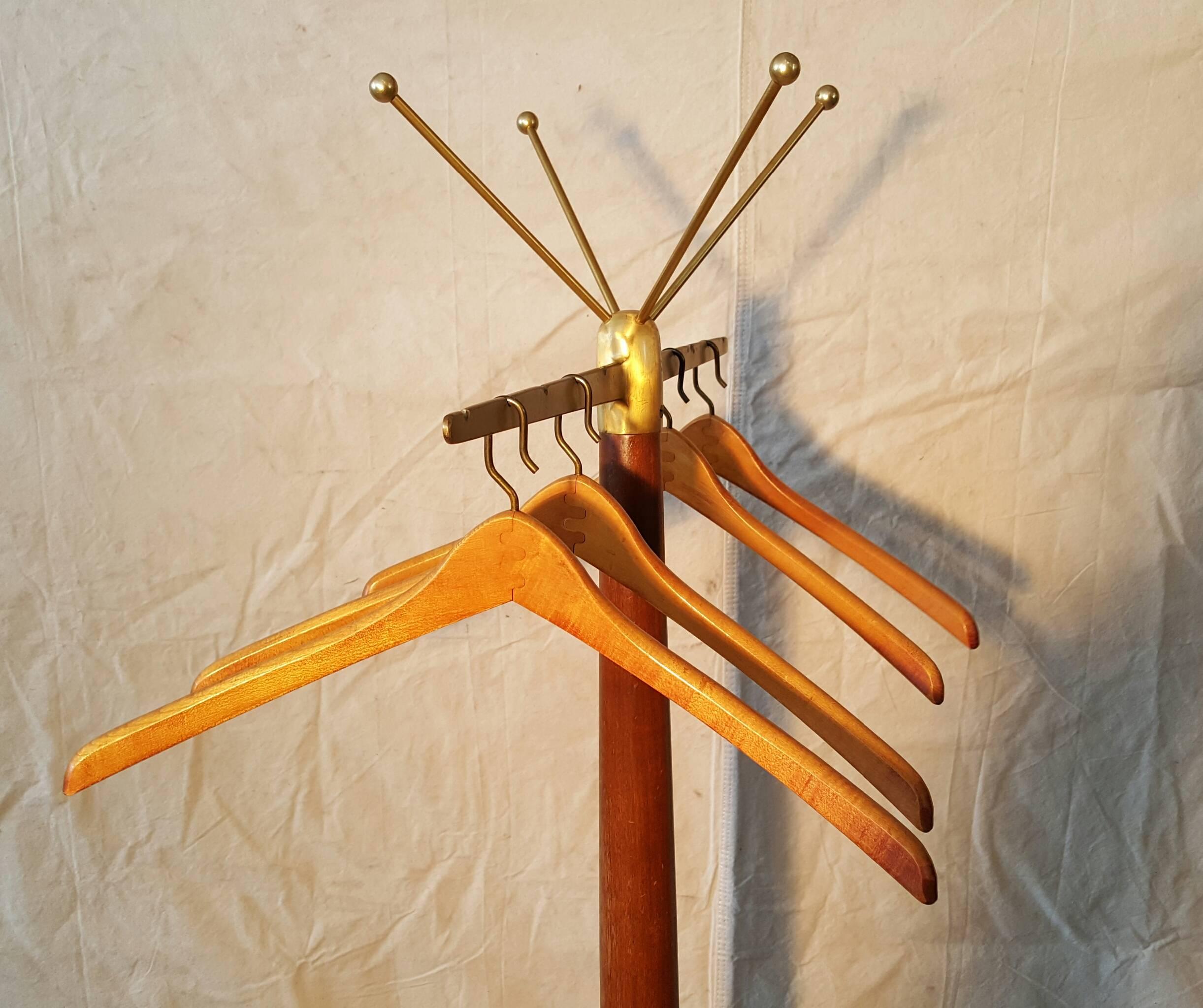 Elegant coat stand in the manner of Gio Ponti with solid brass four legged base, Whimsical brass ball feet. Top, mirror image of base, brass arms, balls, retains four original walnut and brass hangers, interesting joinery solid walnut body with