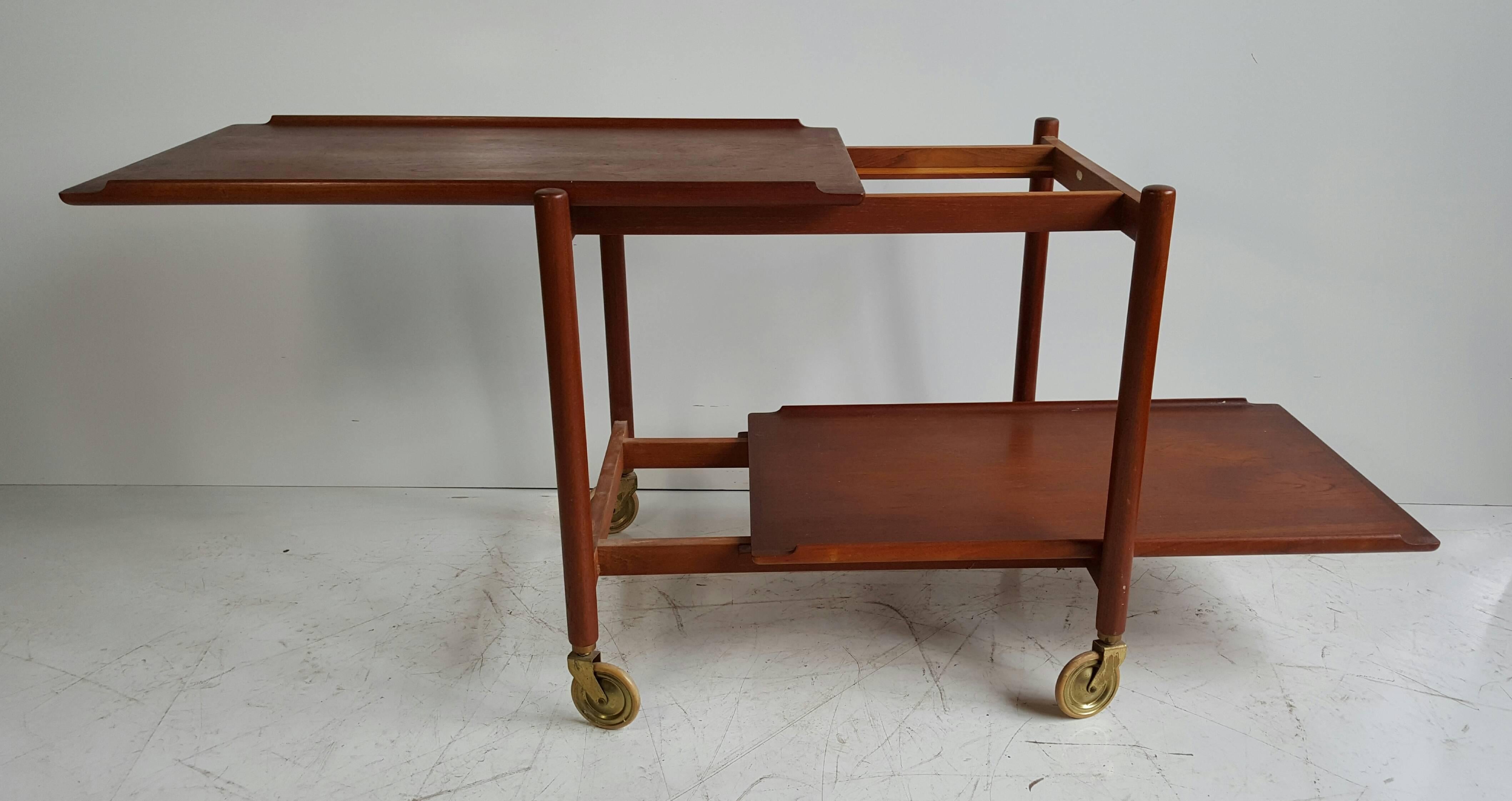 Classic Modernist rolling bar or tea cart made in Denmark. Wonderful, simple design. Removable sliding serving trays, solid teak and rosewood construction.