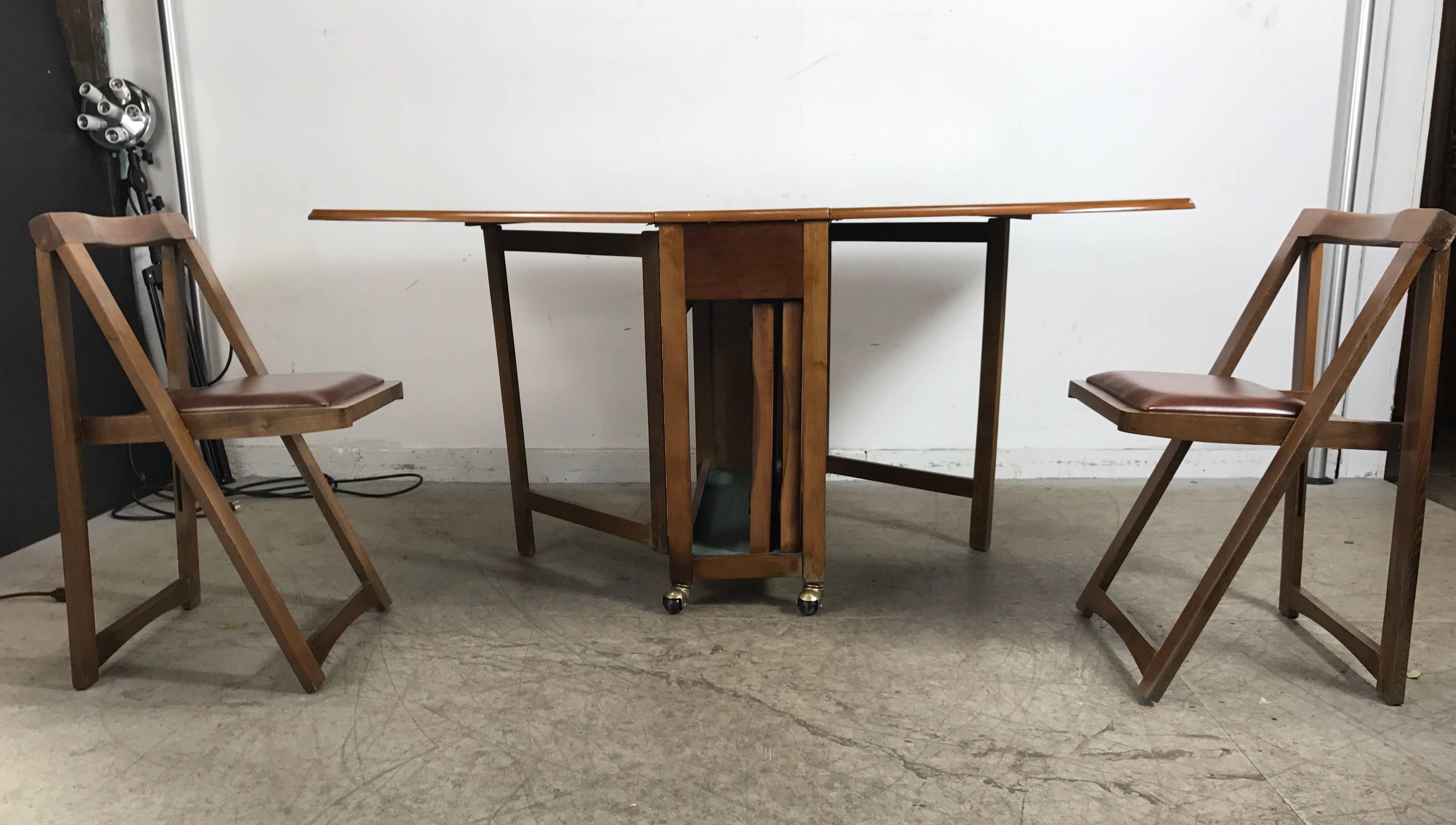 Modernist suitcase dining table ,fold down, compact self stored chairs, amazing design, richly grained wood top. Table open measures 51 inches x 34 inches x 29.5 inches high when closed. Measures 34 inches x 14 inches x 29.5 inches high and neatly