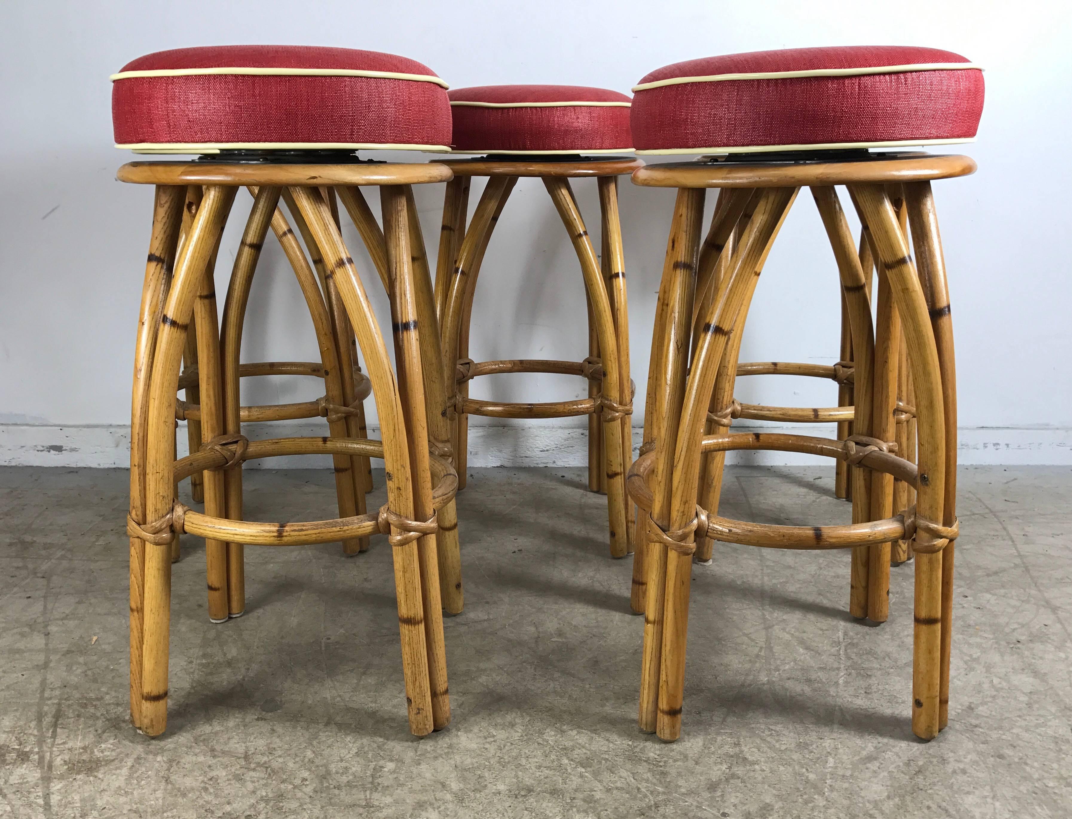 Classic Mid-Century Modern design, set of five bamboo swivel bar or counter stools, beautiful original finish, new upholstered tops. Stunning.