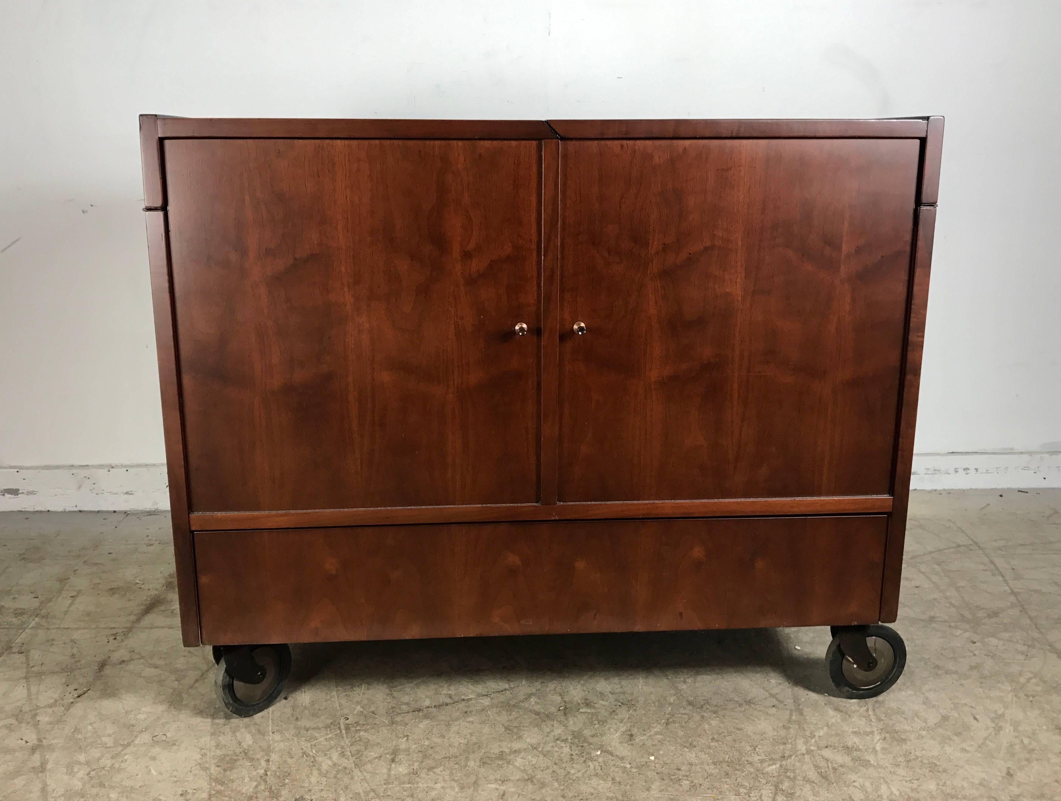 Classic Mid-Century Modern portable rolling fold out bar cart. Beautifully
grained walnut wood, top two panels open for glasses and serving, as well as bottom drawer, also centre surface opens for generous liquor bottle storage, retains original