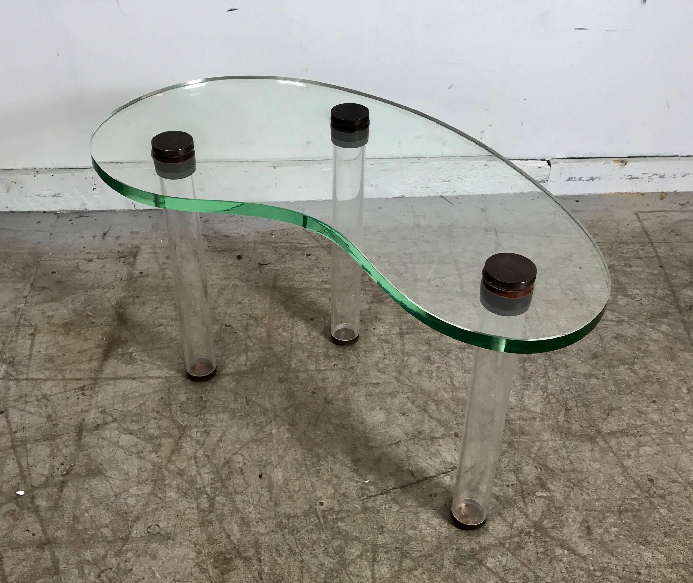 Super rare cocktail table designed by Gilbert Rohde, manufactured by Herman Miller in 1939. One inch thick kidney shape polished plate glass, Lucite cylinder legs. Brass caps and feet, incredible design, beautiful original condition. Examples found