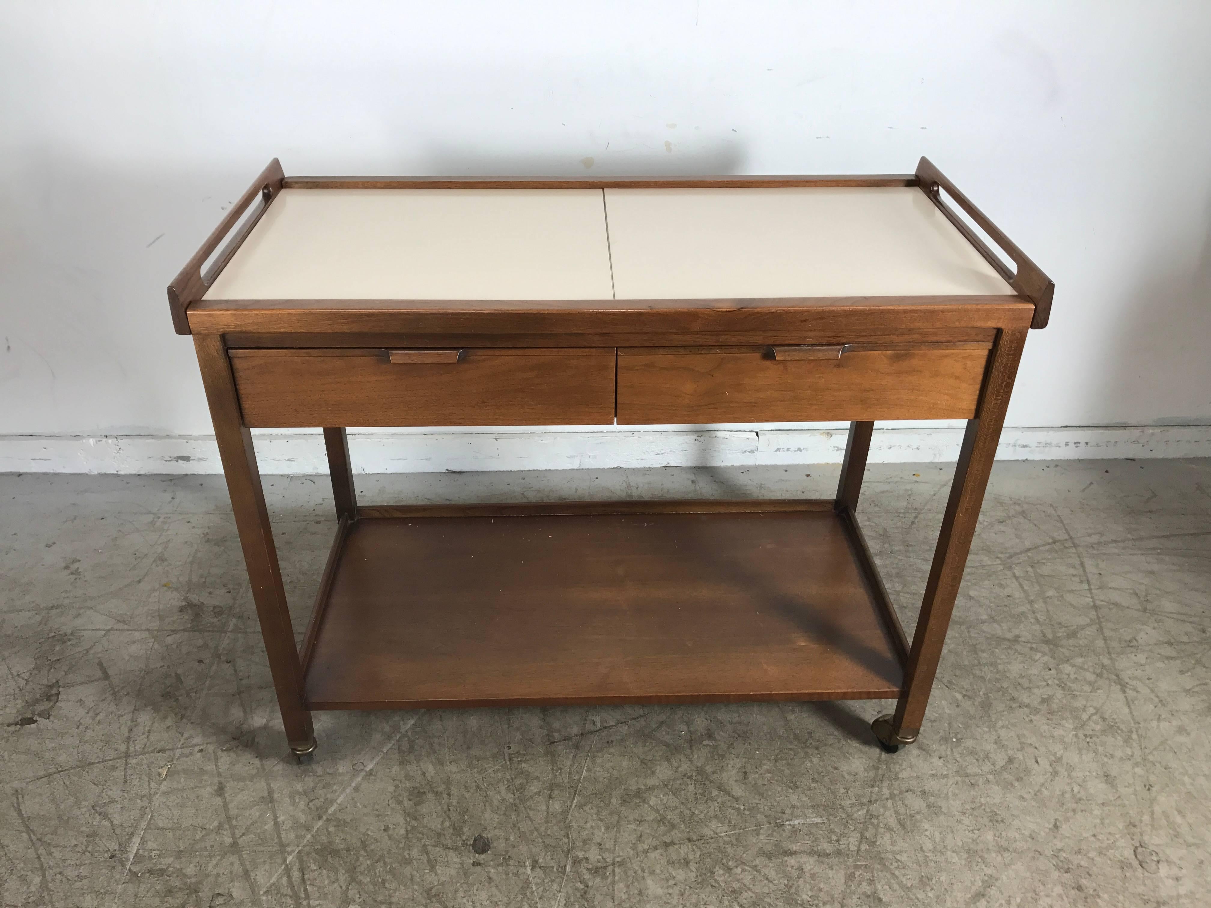 Classic Mid-Century Modern walnut expandable rolling bar cart or server, Manufactured by American of Martinsville, designed by Merton L. Gershun. Expanding white laminate sliding top opens to 56 inches, two drawers. Solid walnut construction, fit