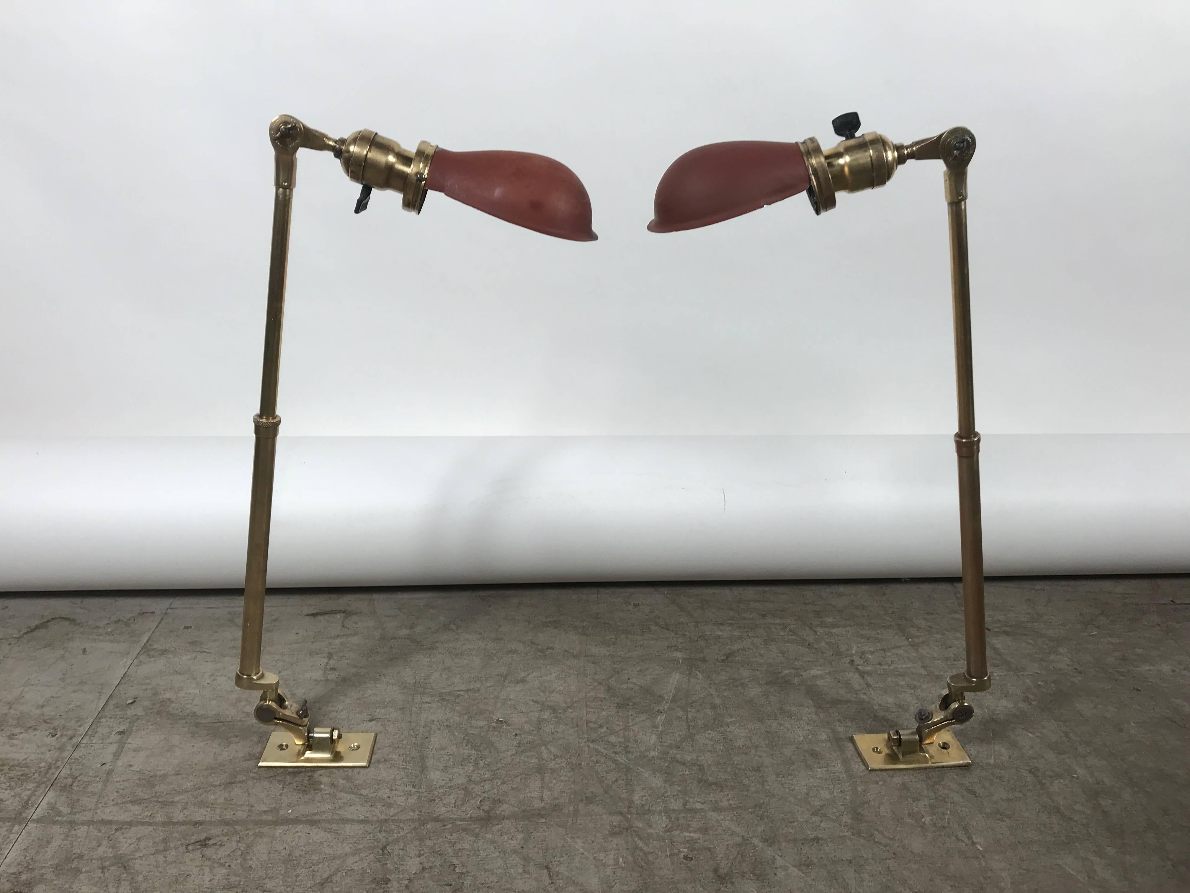 Matched pair of polished brass O C White Industrial task or work lamps. Beautifully polished telescopic adjustable standards. From 14 to 19 inches, salmon with white interior color metal shades.