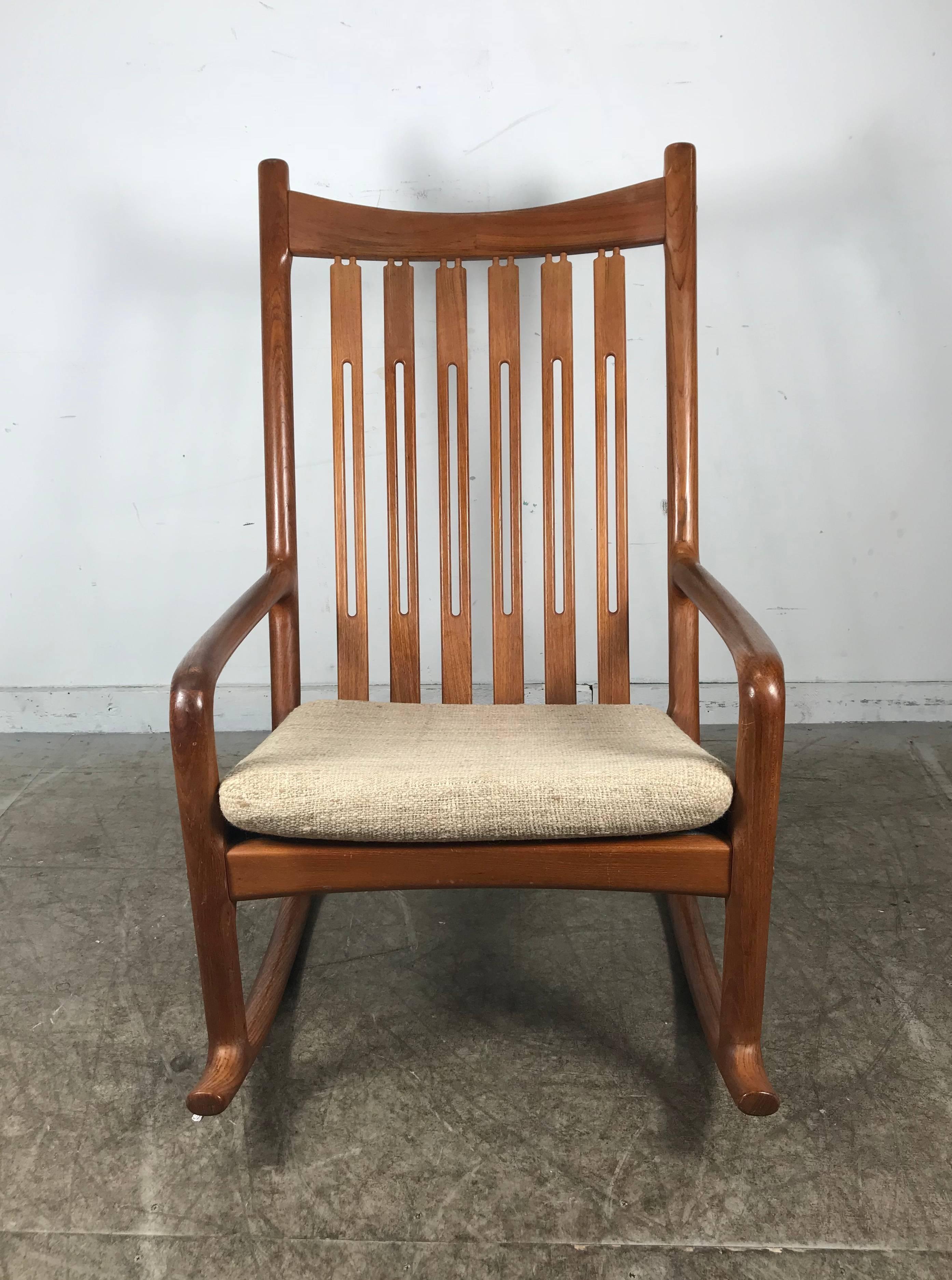 Sculpted teak rocking chair designed by Hans Olsen and made by Juul Kristensen.

Beautiful back detail and classic Danish craftsmanship. Bentwood arms and down cushion provide superb comfort.

Chair is in excellent condition with minimal signs