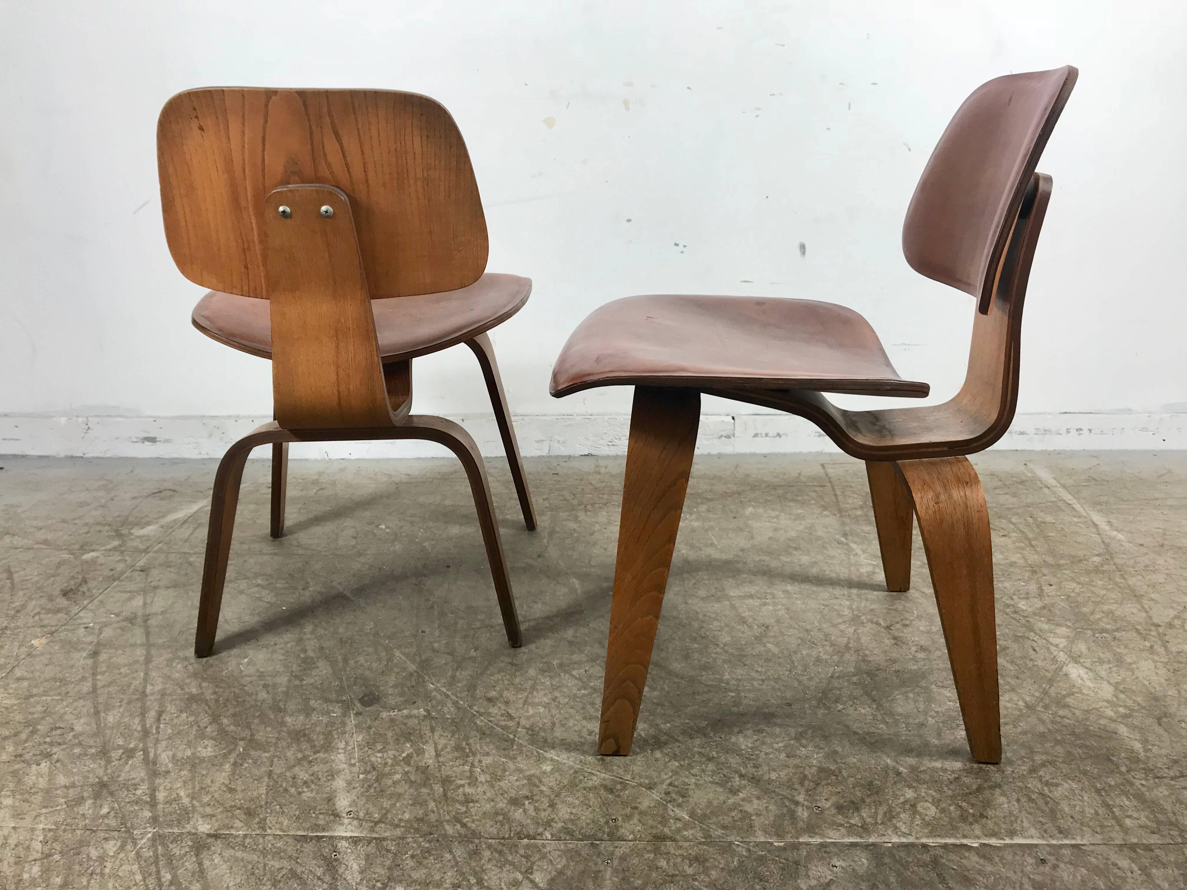 Rare early production Pair Leather and Walnut Plywood D C W's (DINING CHAIR WOOD) designed by Charles and Ray Eames, manufactured by Herman Miller / Evans.Original salmon color leather seat and  back,
An exceptional original matched pair of  LCW's